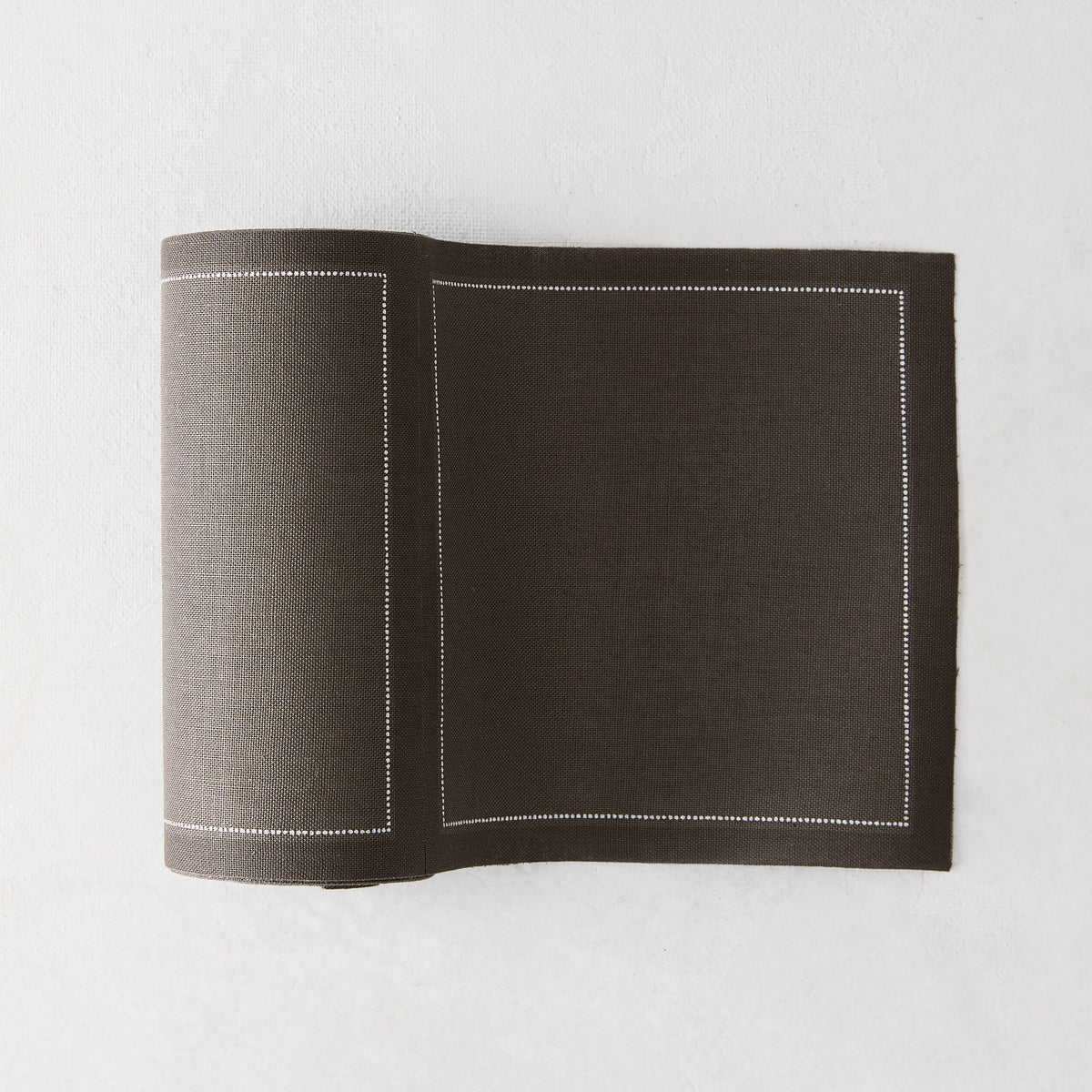 Anthracite grey tear-off cotton cocktail napkins, roll of 50, with a white stitched border.