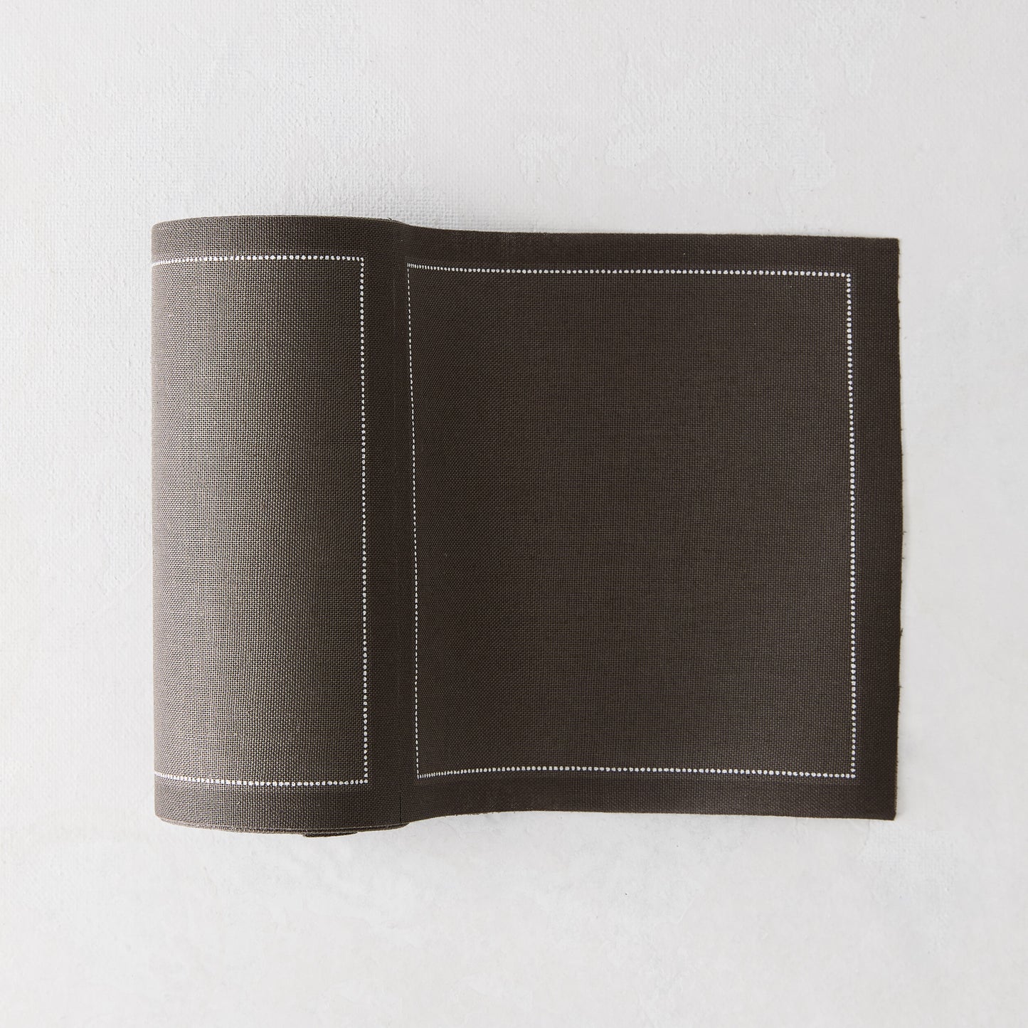 Anthracite grey tear-off cotton cocktail napkins, roll of 50, with a white stitched border.