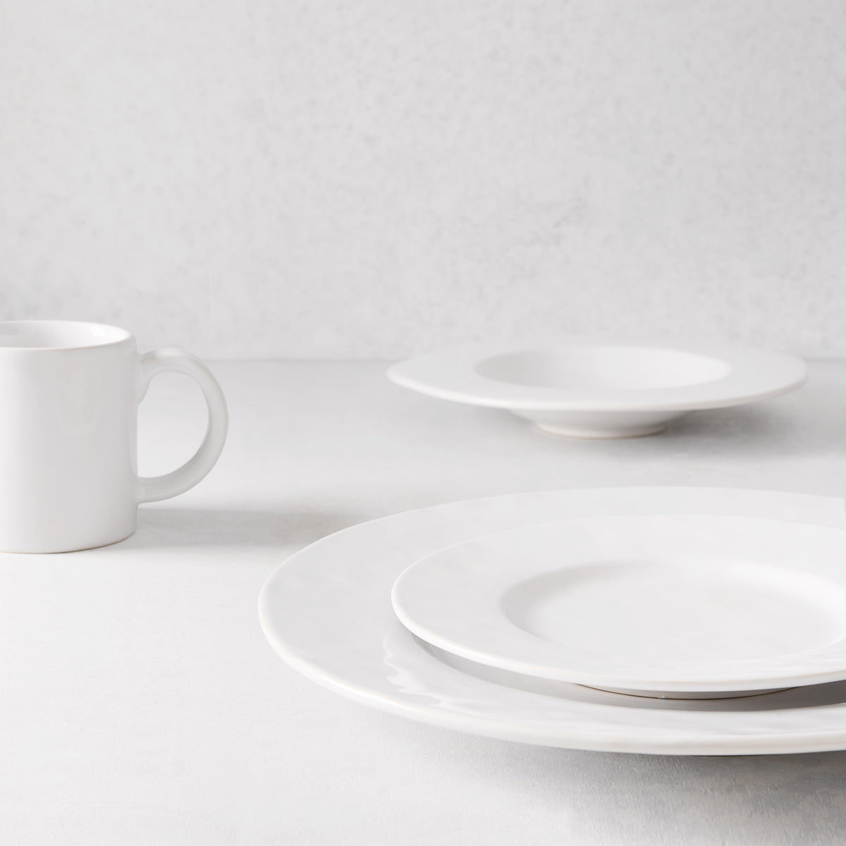 Artisan creamy white stoneware oversized dinner plate with wide lip, salad plate, soup bowl, and mug.