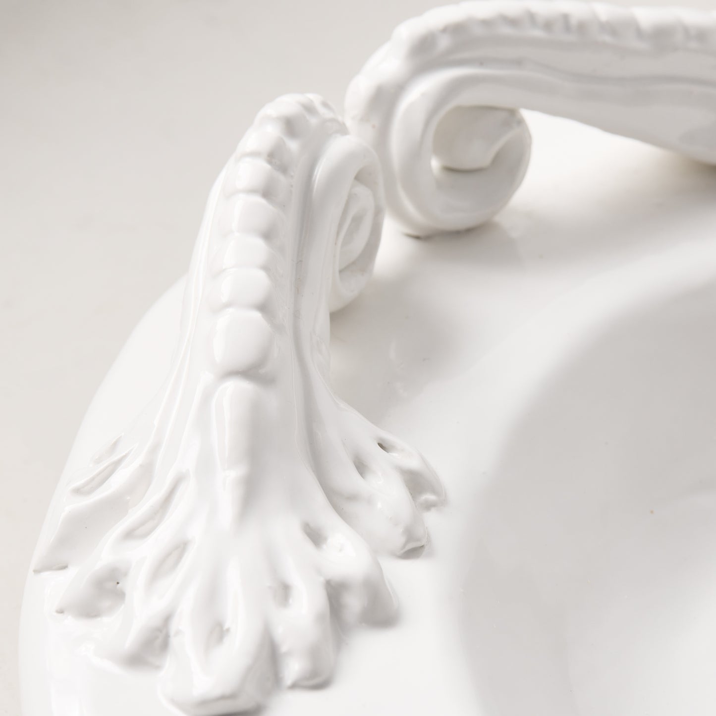 White ceramic oval serving platter with intricate artisanal handles.