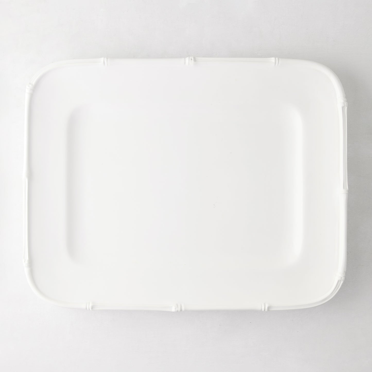 White ceramic rectangular serving platter with bamboo-molded edge.