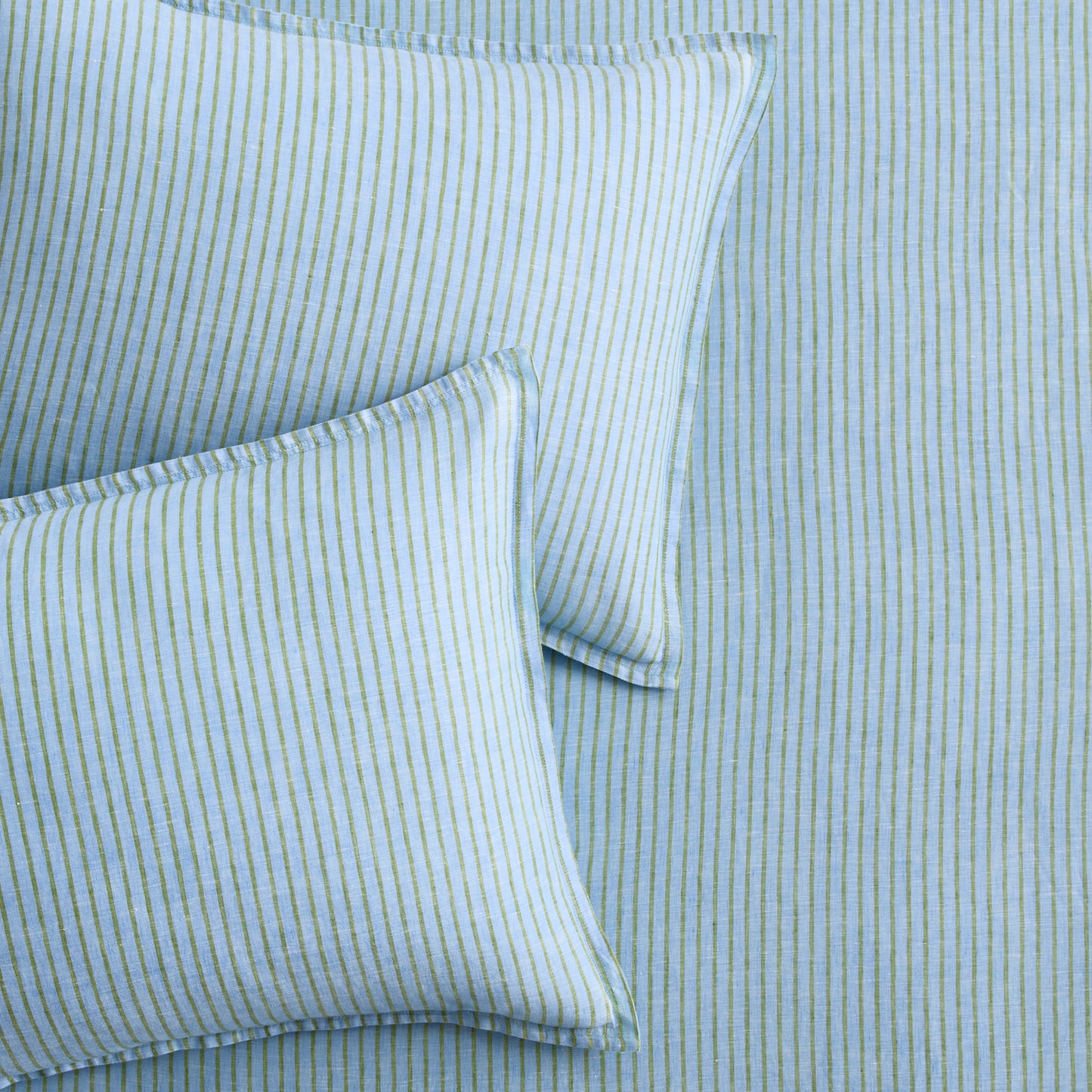 Two blue and green striped European washed linen euro shams on matching striped bedding.
