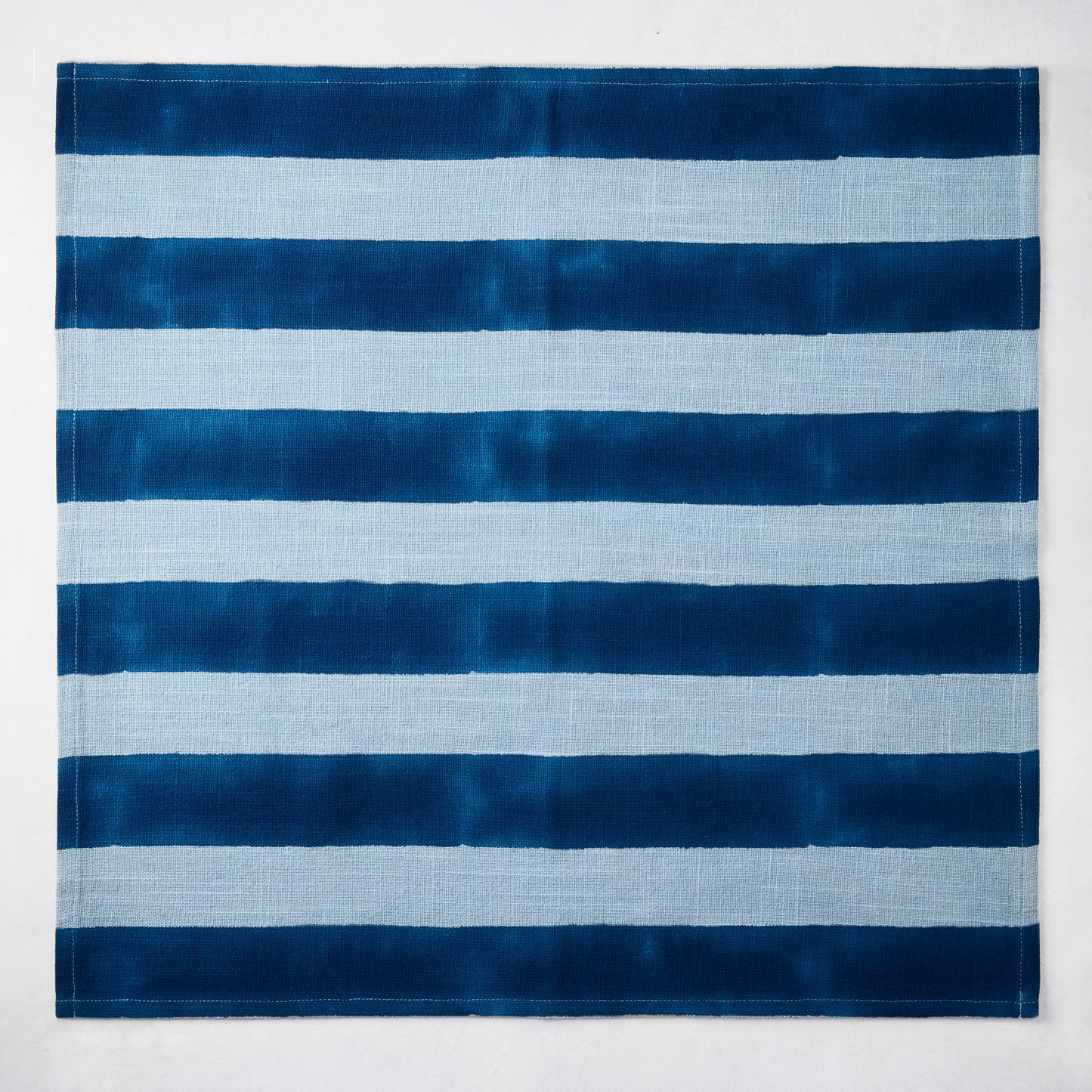 Blue Tonal Hampton Stripe Cotton Napkin, 22" square, with bold and light blue horizontal stripes.