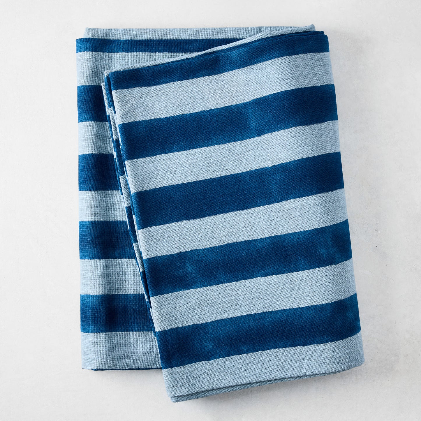 Blue Tonal Hampton Stripe Cotton Tablecloth, 70"W x 108"L, folded with bold and light blue stripes.