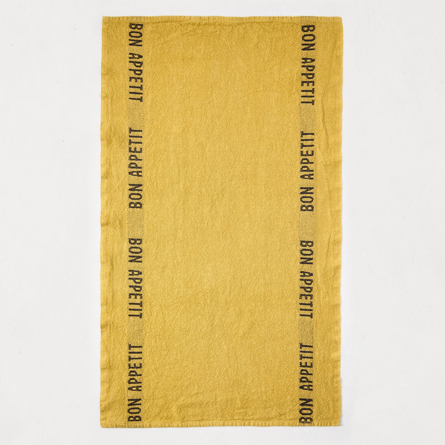Goldenrod yellow linen hand towel with "Bon Appetit" in black lettering along both long edges.