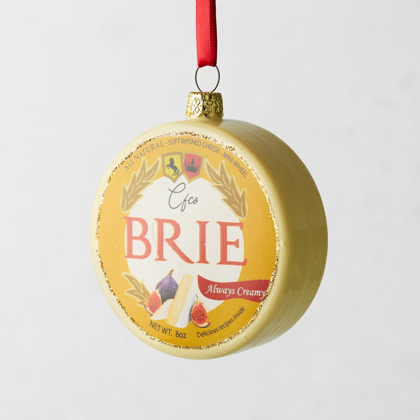 Round glass Brie cheese Christmas ornament with gold glitter and red ribbon.