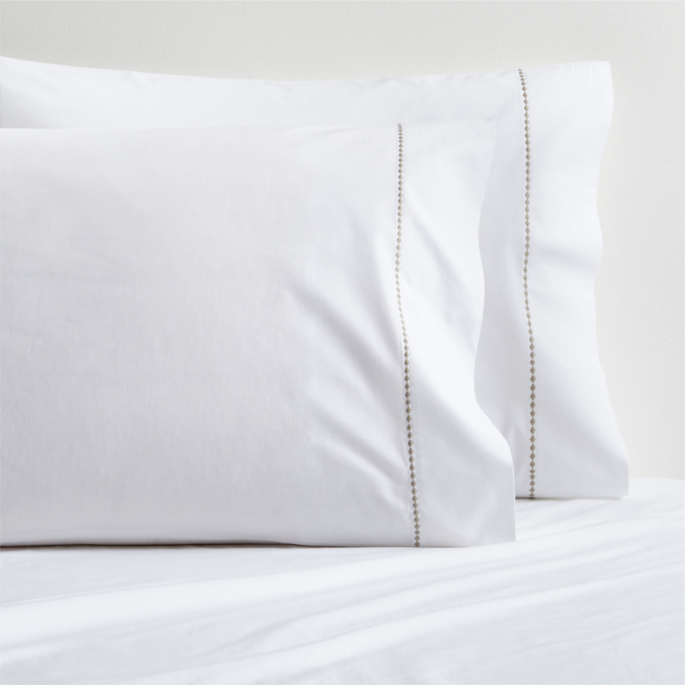 Set of 2 white percale pillowcases with a brown diamond embroidered detail.
