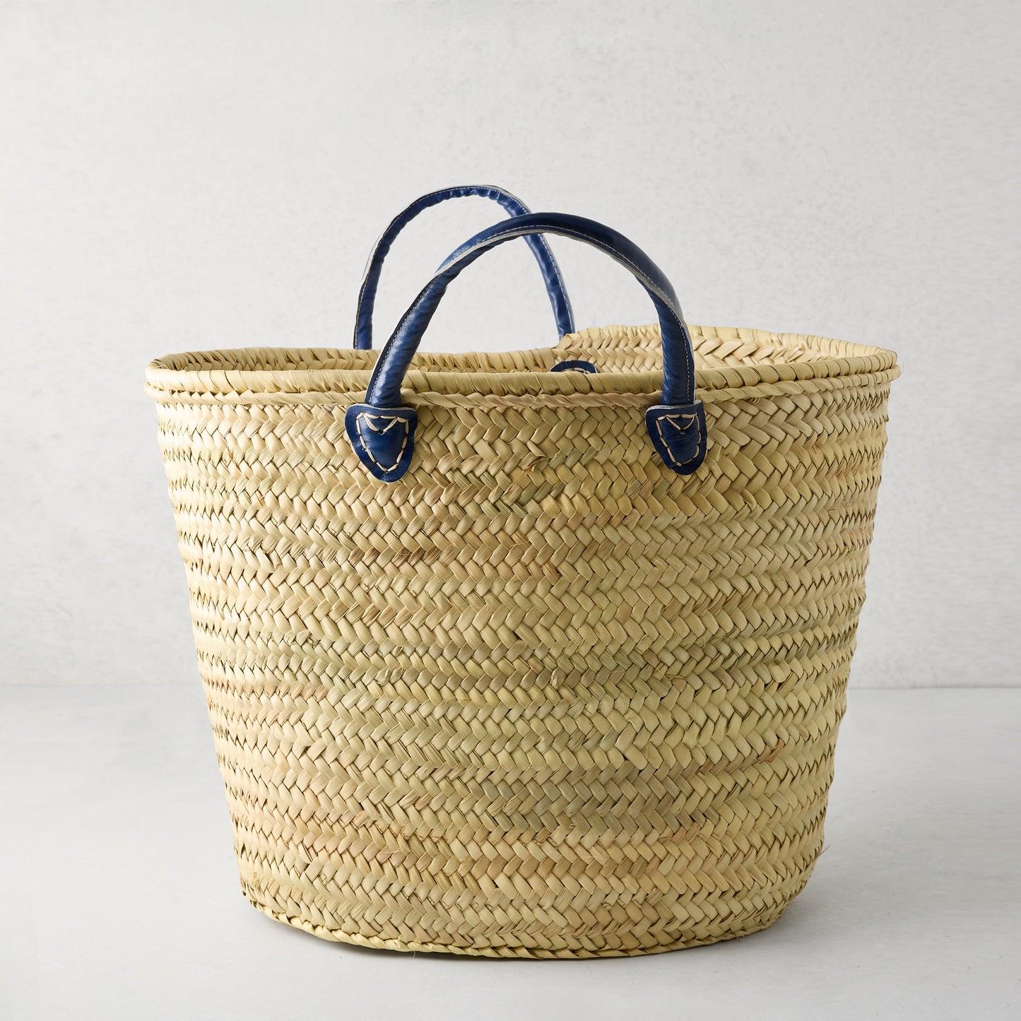 Capri Blue Handled Woven Tote Bag, natural palm grass with navy blue leather handles.