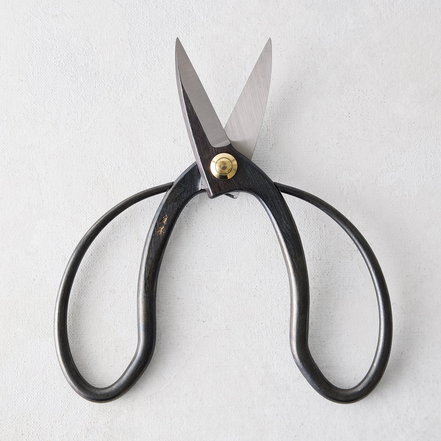 Carbon steel Higurashi garden scissors with dark, uniquely curved handles and a brass pivot.