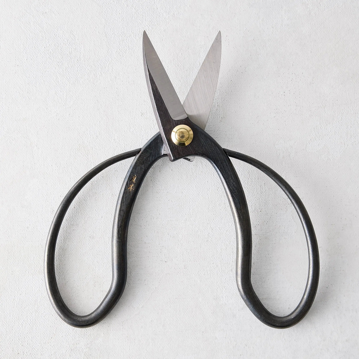 Carbon steel Higurashi garden scissors with dark, uniquely curved handles and a brass pivot.