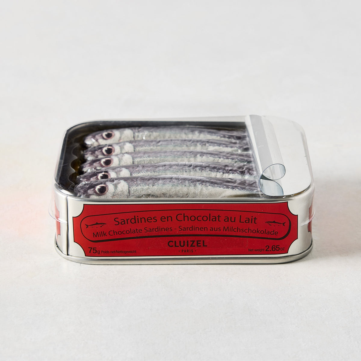 Cluizel Milk Chocolate Tinned Sardines in a silver tin with a red label, showing five chocolate sardines.