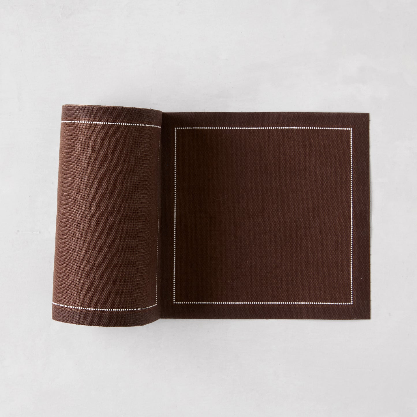 Cocoa brown cotton tear-off cocktail napkin roll with white dotted border.