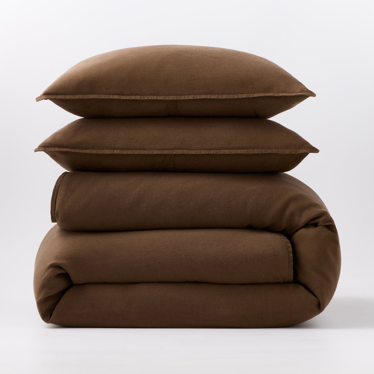 Stacked coffee brown European washed linen duvet and two matching pillow shams on a white background.
