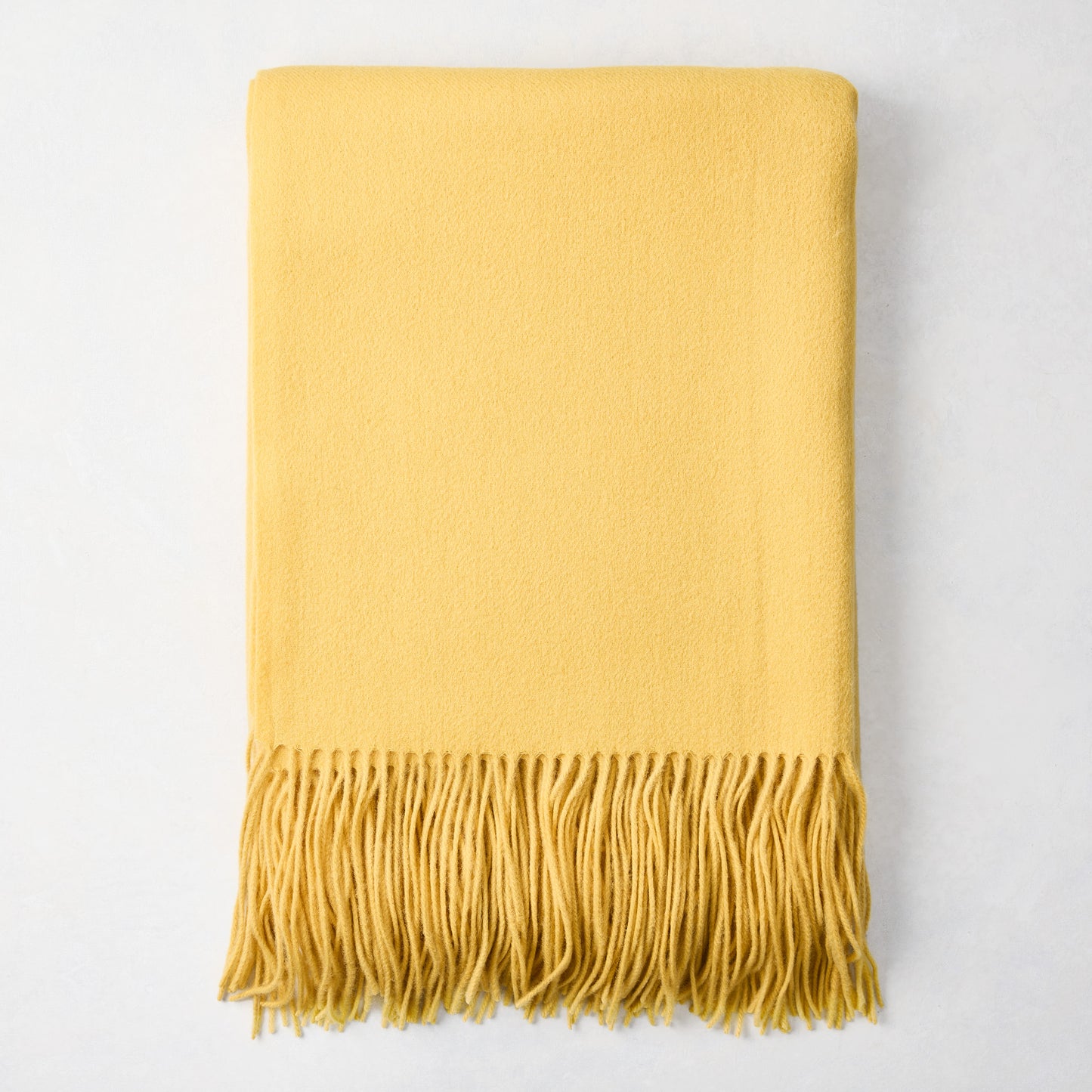 Corn yellow cashmere throw blanket with classic fringe, folded.