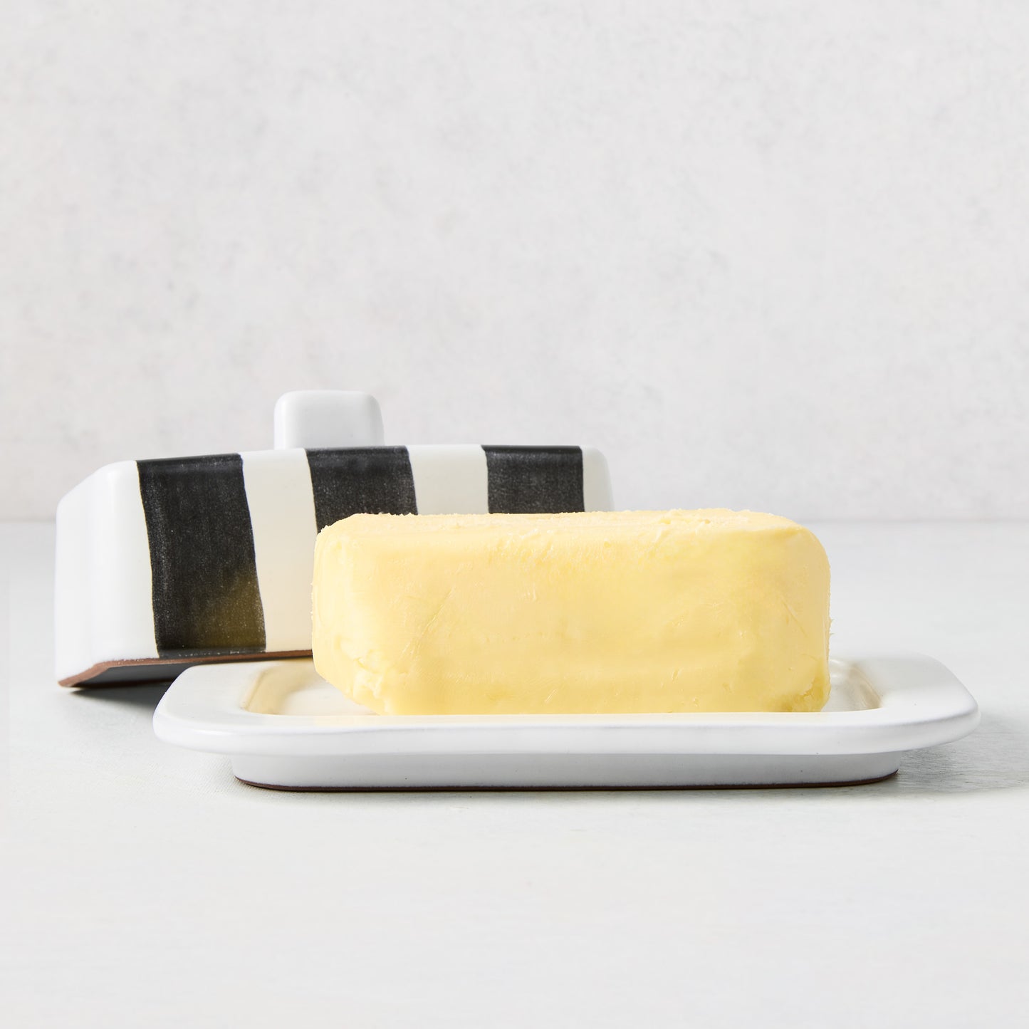 Diane Keaton + Hudson Grace black and white striped stoneware butter dish with lid and stick of butter.