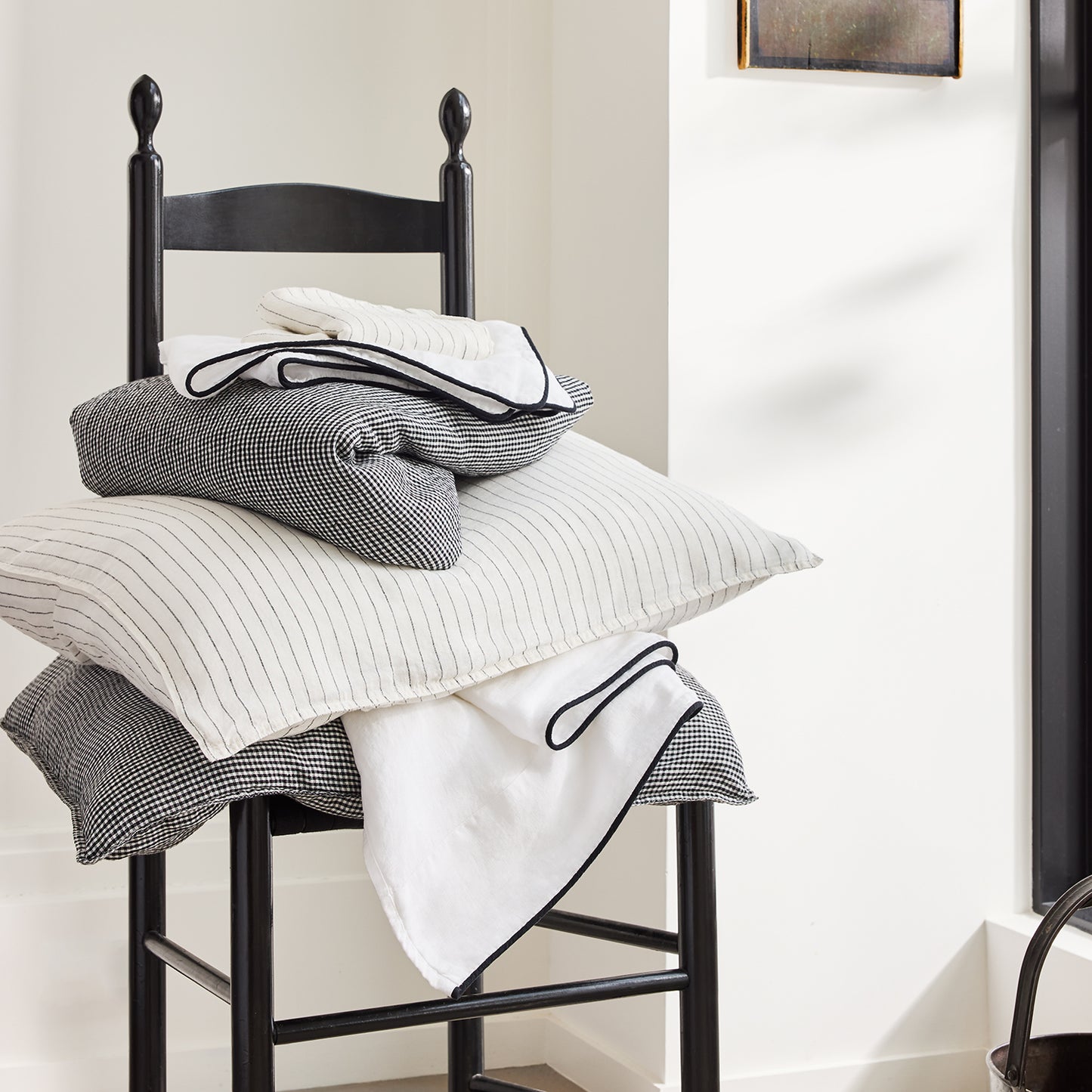Diane Keaton x Hudson Grace black and white petite gingham linen duvet cover and striped pillows on a chair.