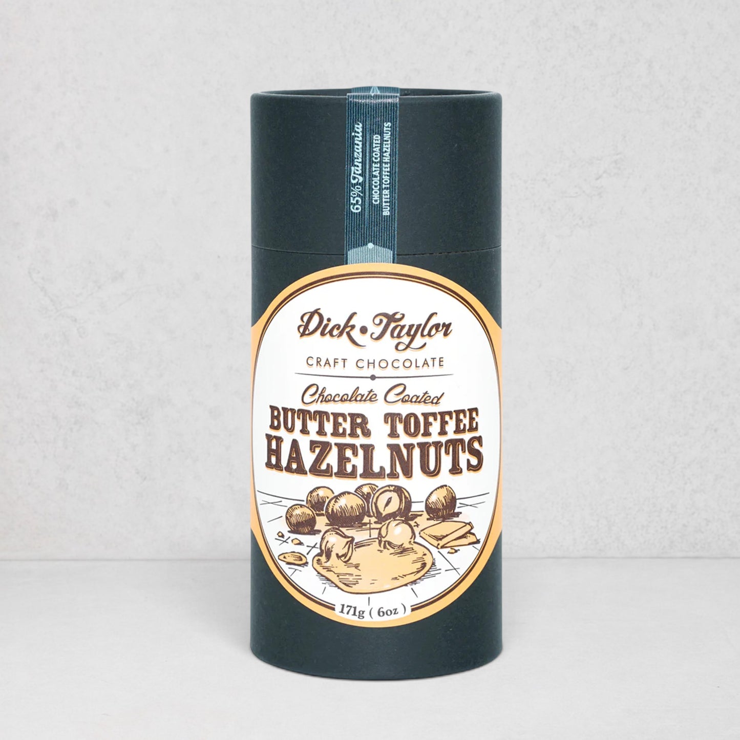 Dick Taylor Chocolate Coated Butter Toffee Hazelnuts in a dark blue cylindrical container with an oval label.