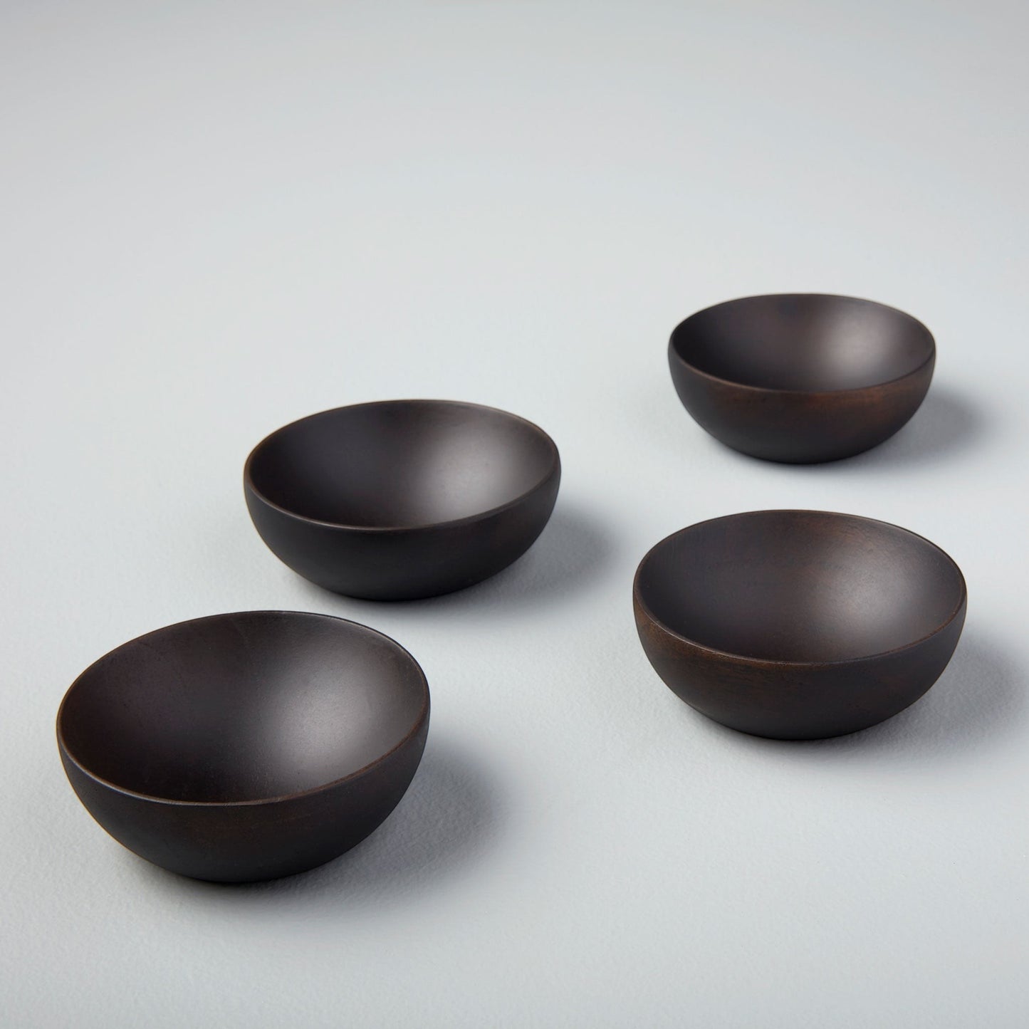 Set of 4 dark ebony teak wood pinch bowls, 2.5" Dia x 1"H, on a light gray surface.