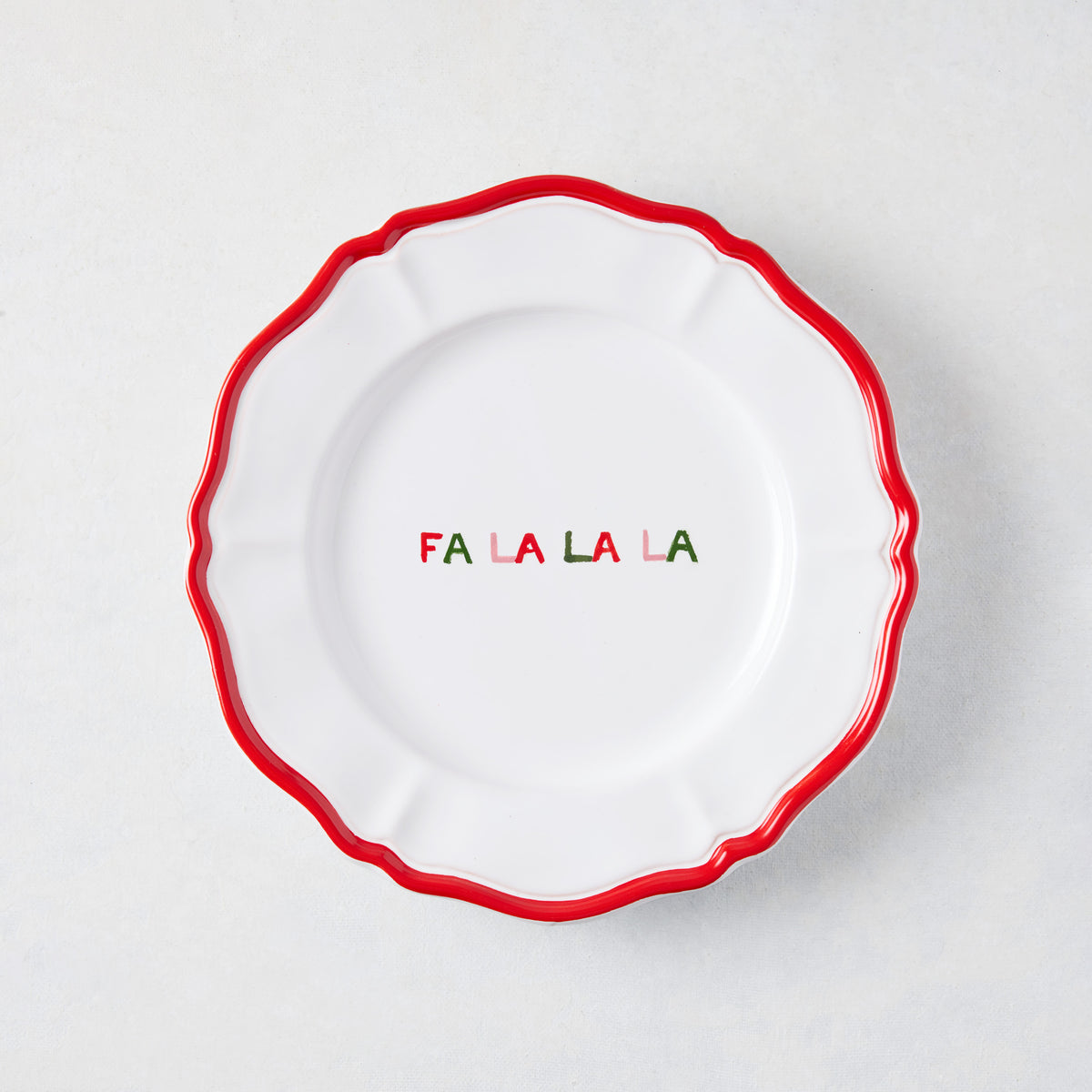 7-inch white ceramic appetizer plate with a scalloped red rim and hand-painted multicolored Fa La La La text.