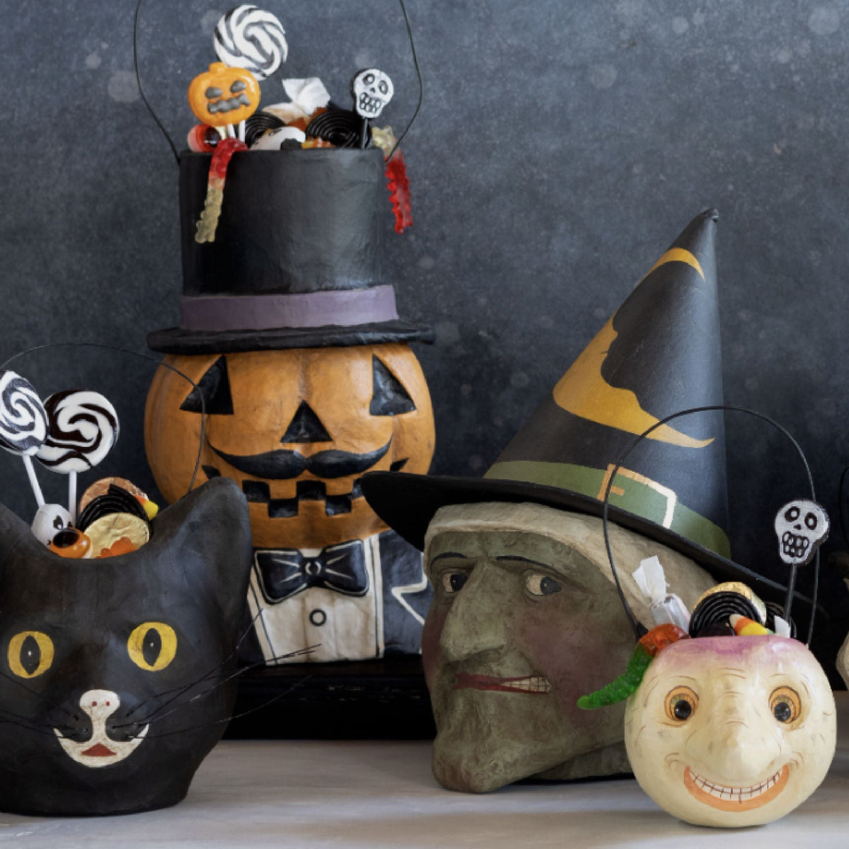 Hand-painted papier-mâché Halloween candy buckets: black cat, pumpkin, witch, skull, owl, and crow.