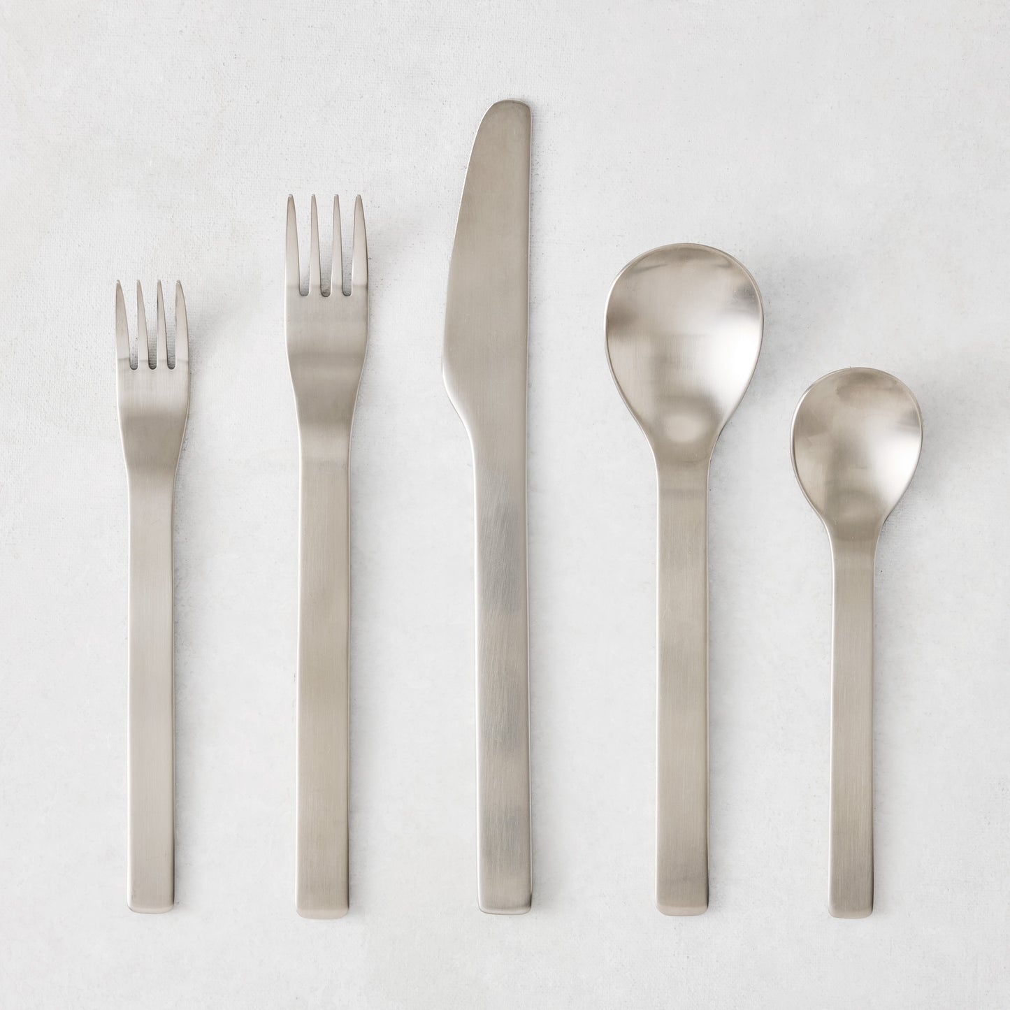 Flint 5-piece flatware set in polished 18/10 stainless steel with a modern, minimalist, rounded design.