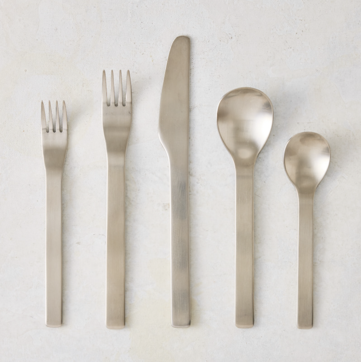 Flint 5-piece flatware set in polished 18/10 stainless steel with a modern, minimal, and rounded design.