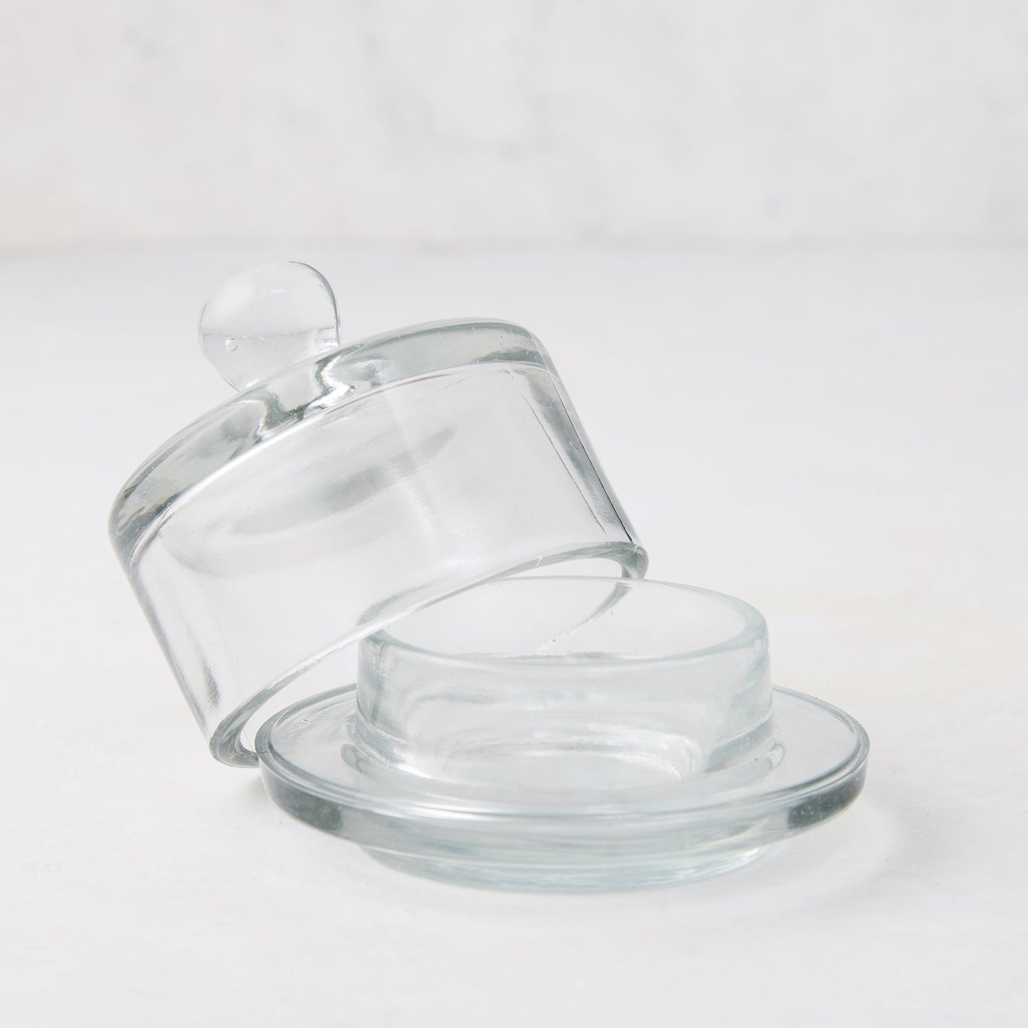 Clear glass butter dish with a domed lid and small knob, resting on a round base.