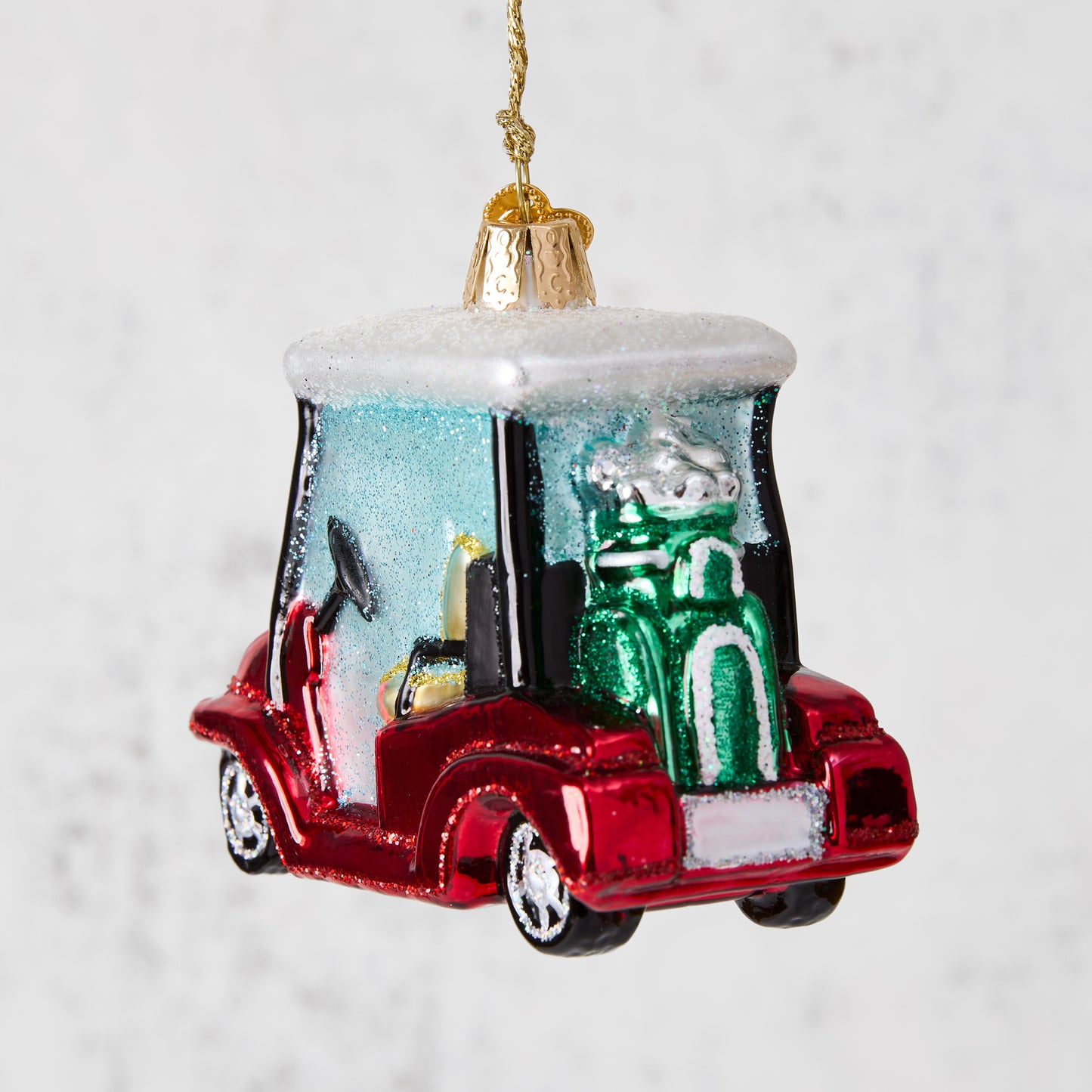 Red glittery glass golf cart Christmas ornament with green golf clubs.