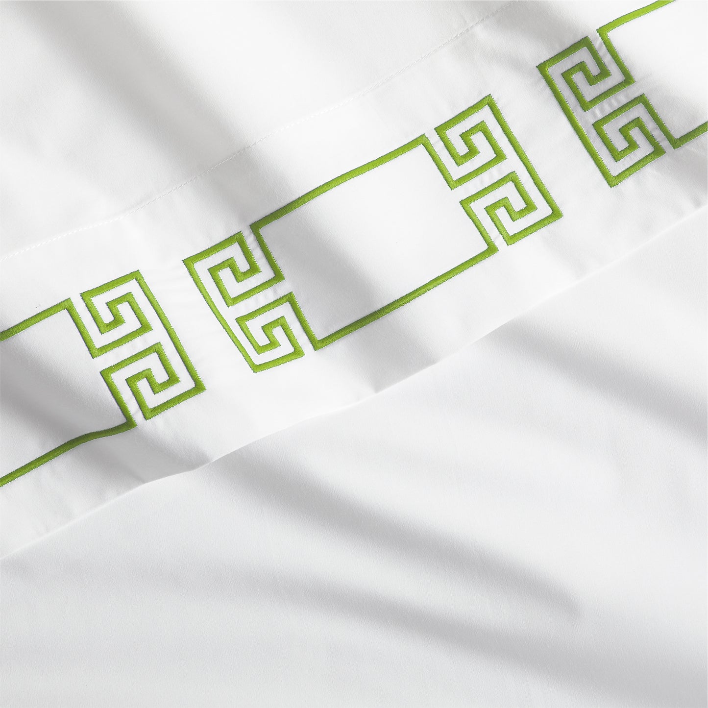 White percale sheet with a bold green embroidered Greek key band.