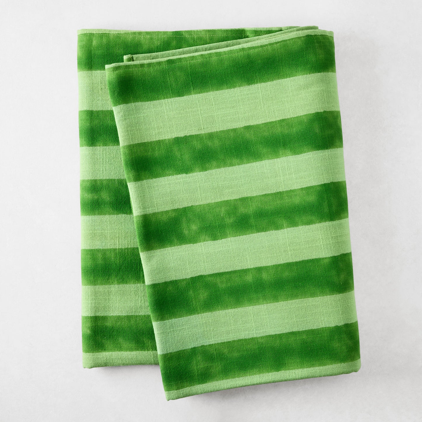 Folded Green Tonal Hampton Stripe Cotton Tablecloth with bold, two-toned green stripes.