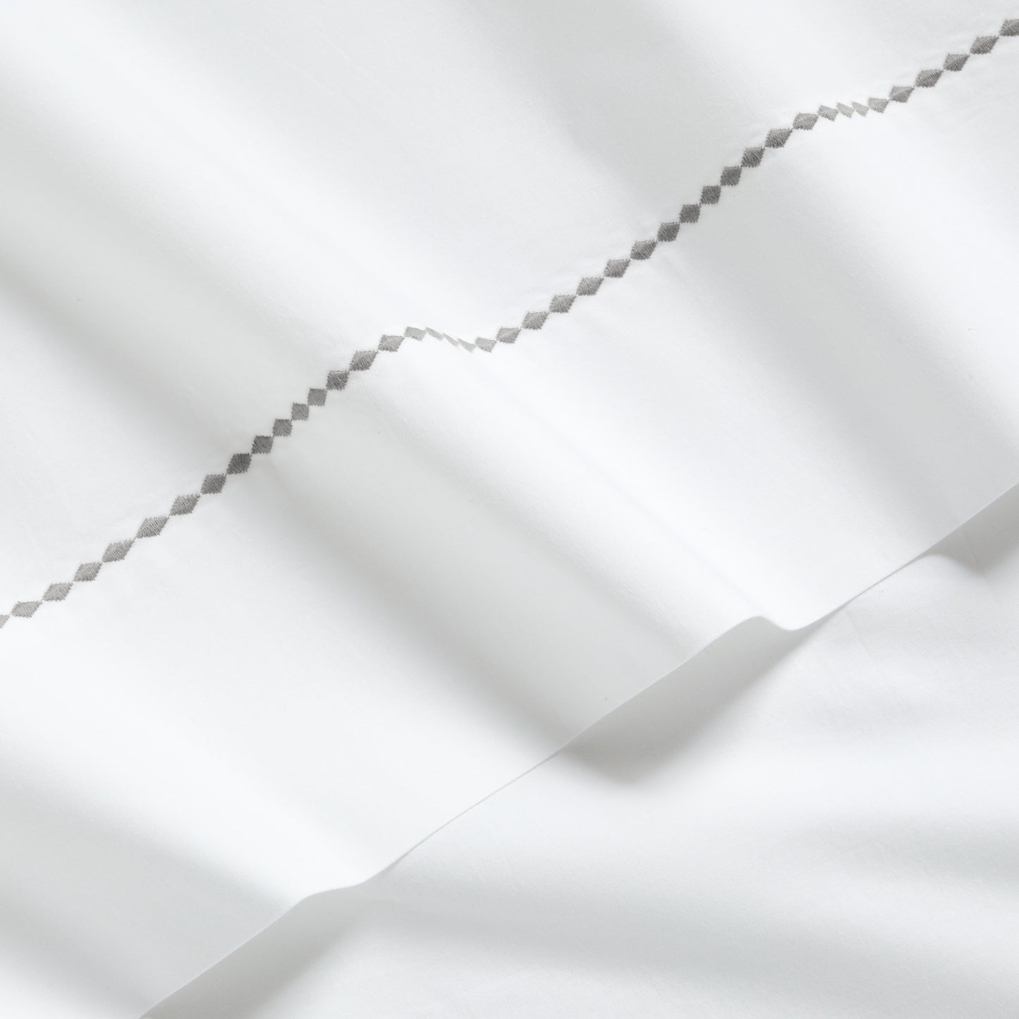 White percale sheet set with a grey diamond embroidered border.