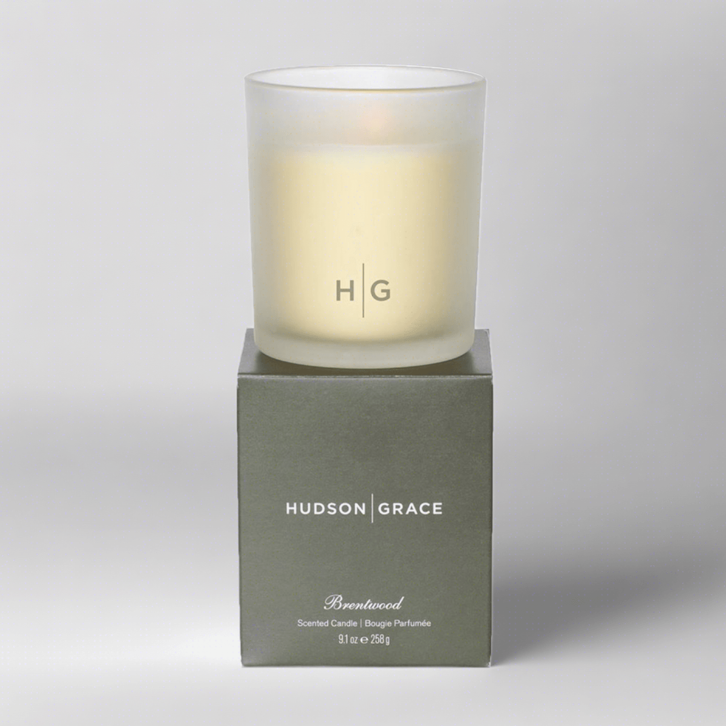 Hudson Grace Brentwood scented candle in a frosted glass vessel with HG logo, on its olive green box.