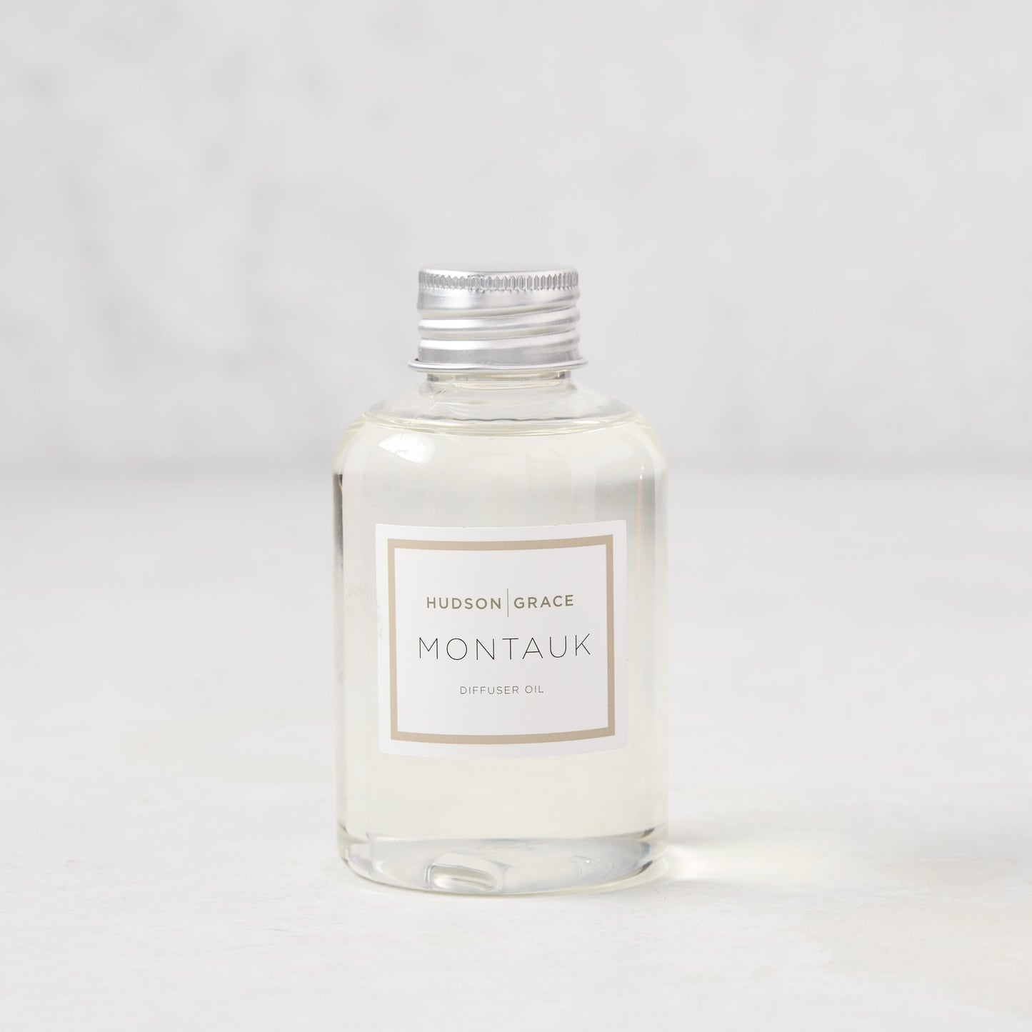 Hudson Grace Montauk Scented Reed Diffuser oil bottle, clear glass with silver cap and white label.