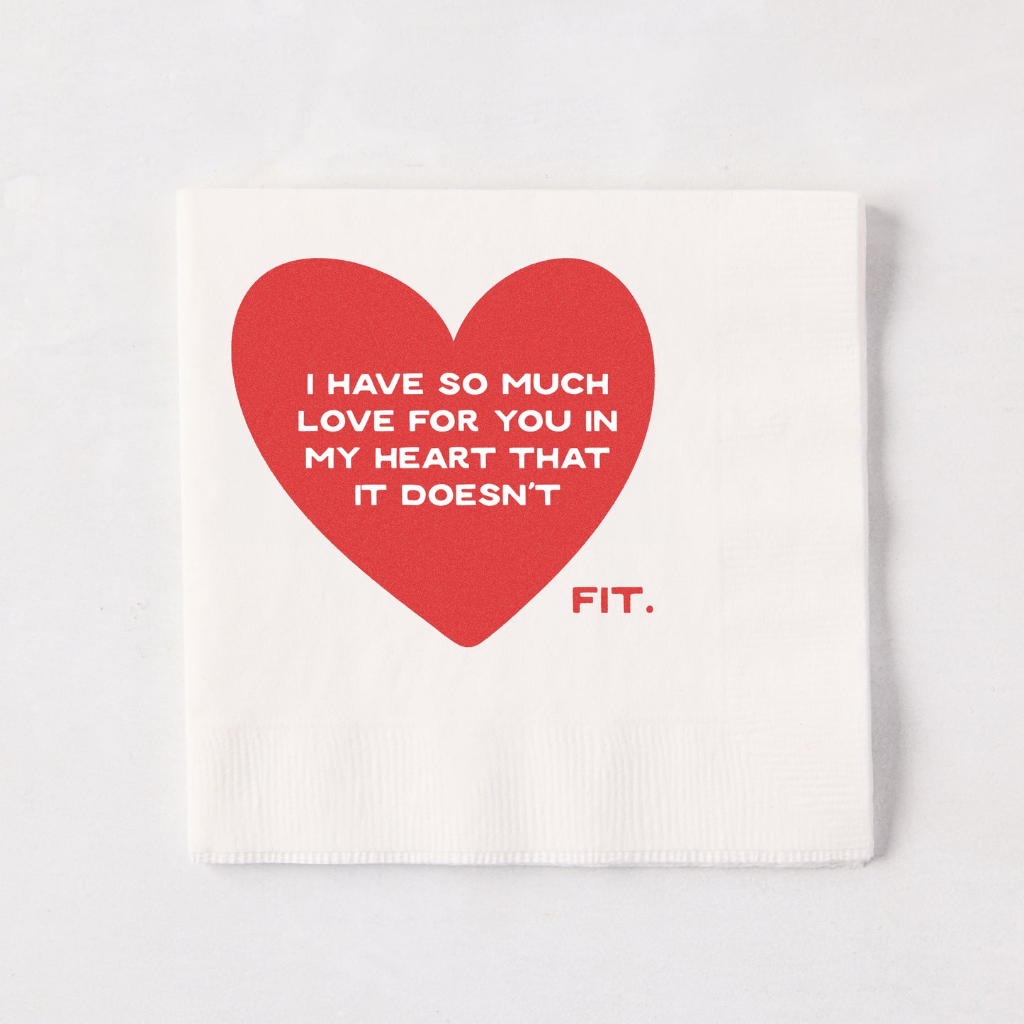 White 5.5" square paper cocktail napkin with a large red heart and "I HAVE SO MUCH LOVE FOR YOU IN MY HEART THAT IT DOESN'T FIT." text.