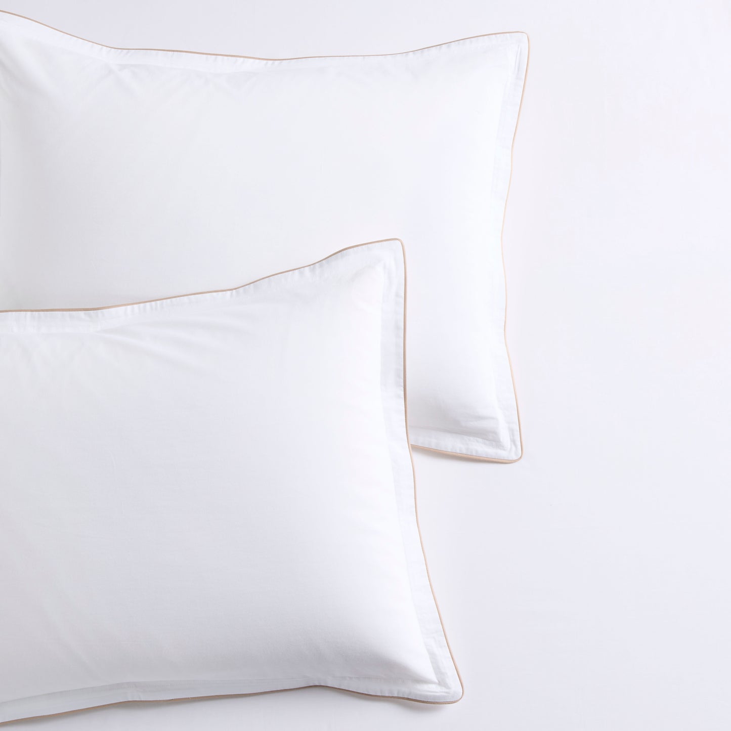 Two white percale pillow shams with khaki piping and subtle double-stitch detailing.