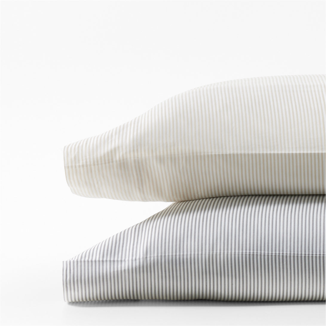 Stacked khaki and grey striped cotton-chambray pillowcases.