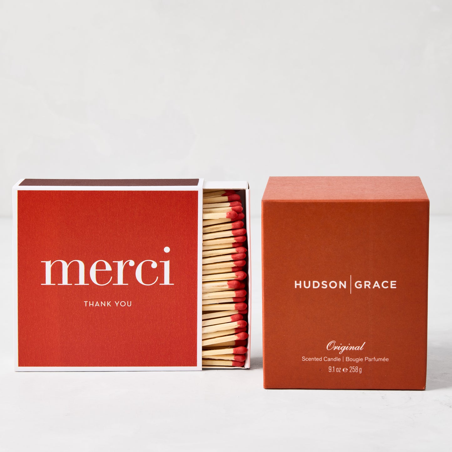 Red "merci" boxed matches with long wooden sticks and a matching Hudson Grace candle.