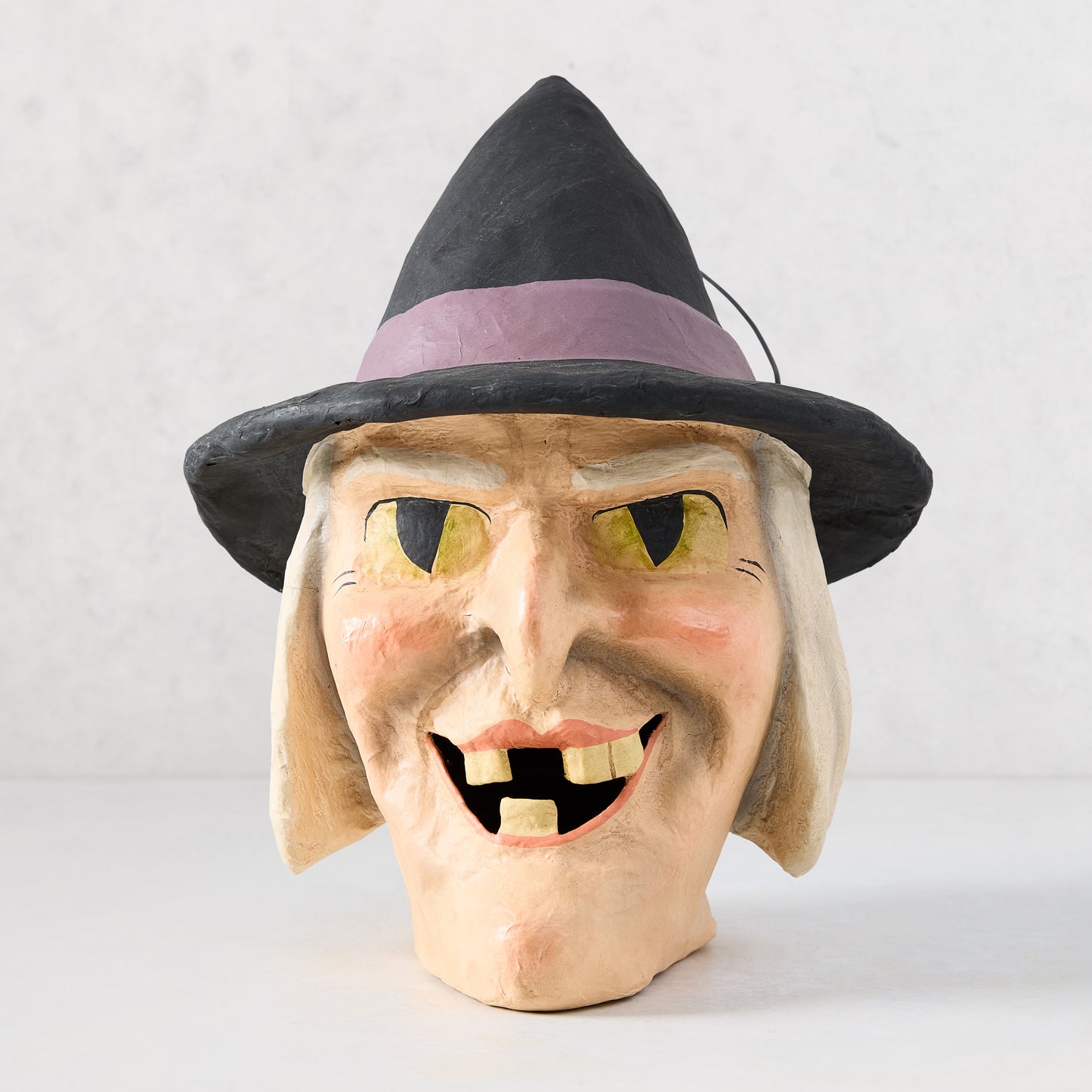 Vintage-style papier-mâché witch candy bucket with a black hat, yellow eyes, and distressed finish, 12 inches tall.