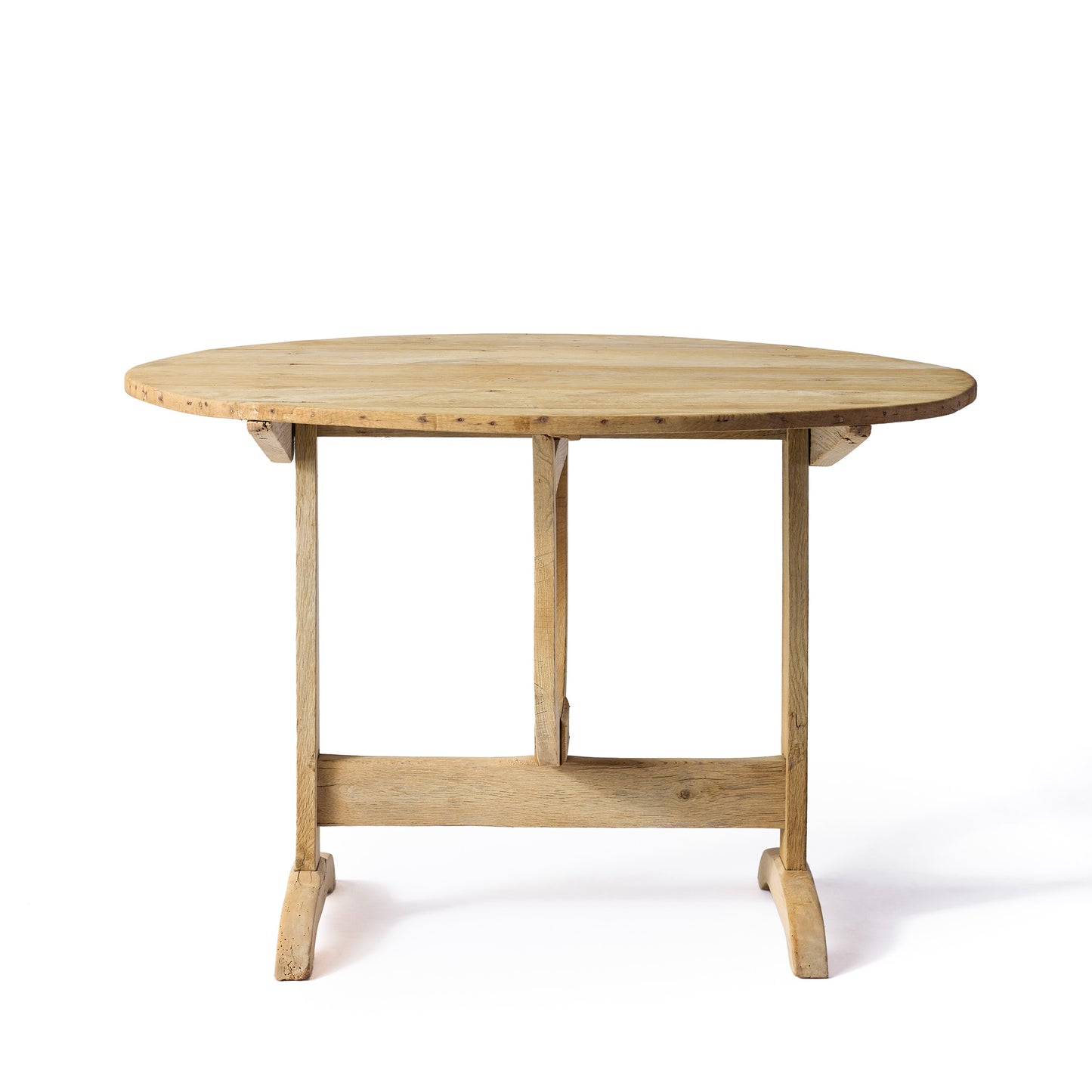 Vintage French bleached oak wine tasting table with a round top and trestle base on a white background.
