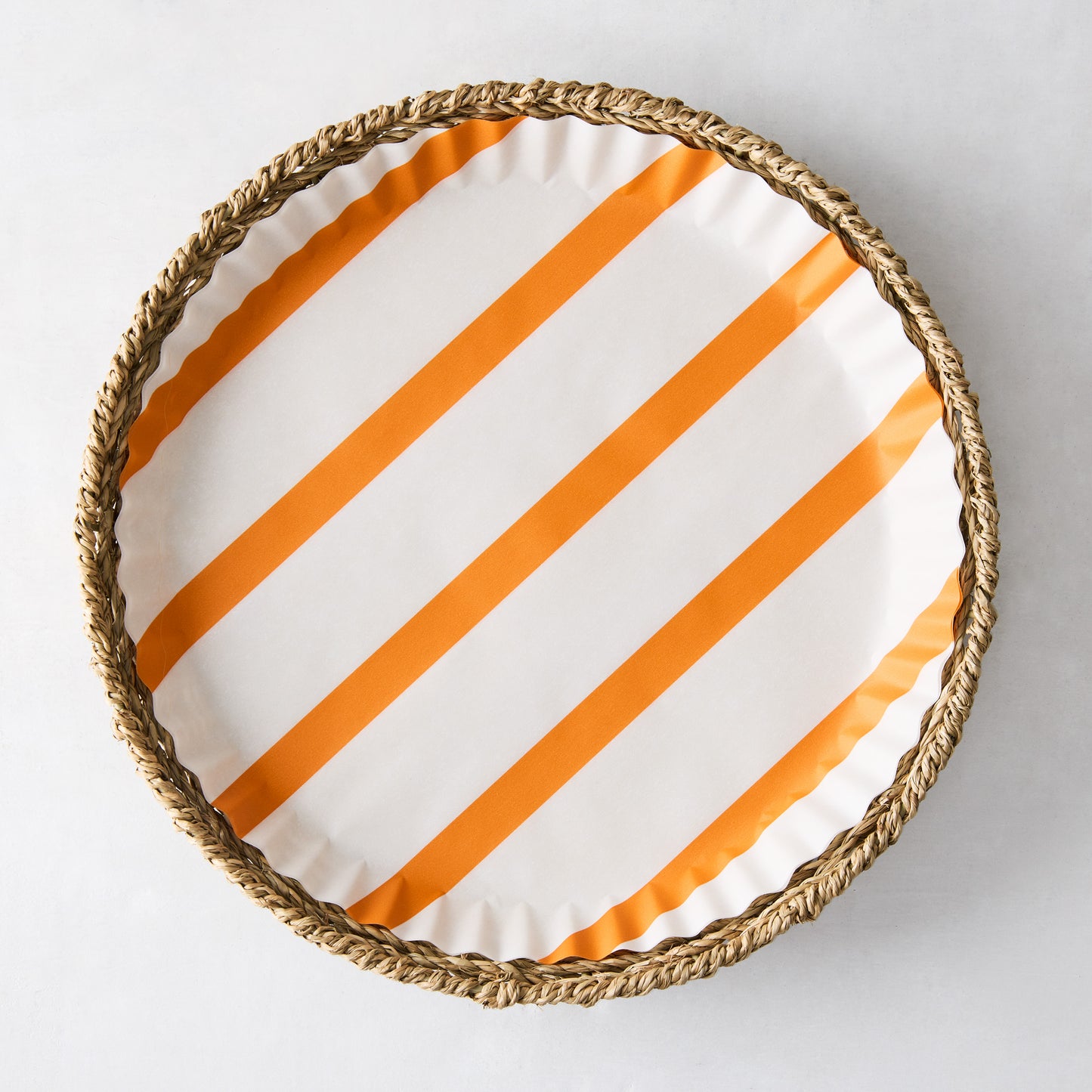 Round parchment liner with orange diagonal stripes inside a woven wicker tray.