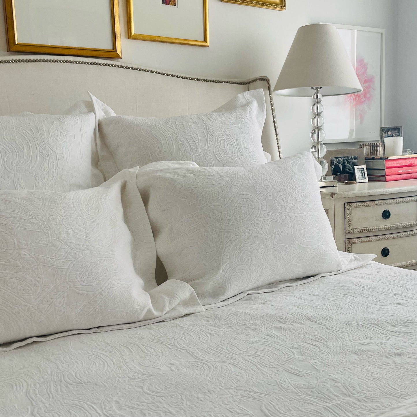White cotton matelassé coverlet and shams with subtle paisley pattern on a bed.