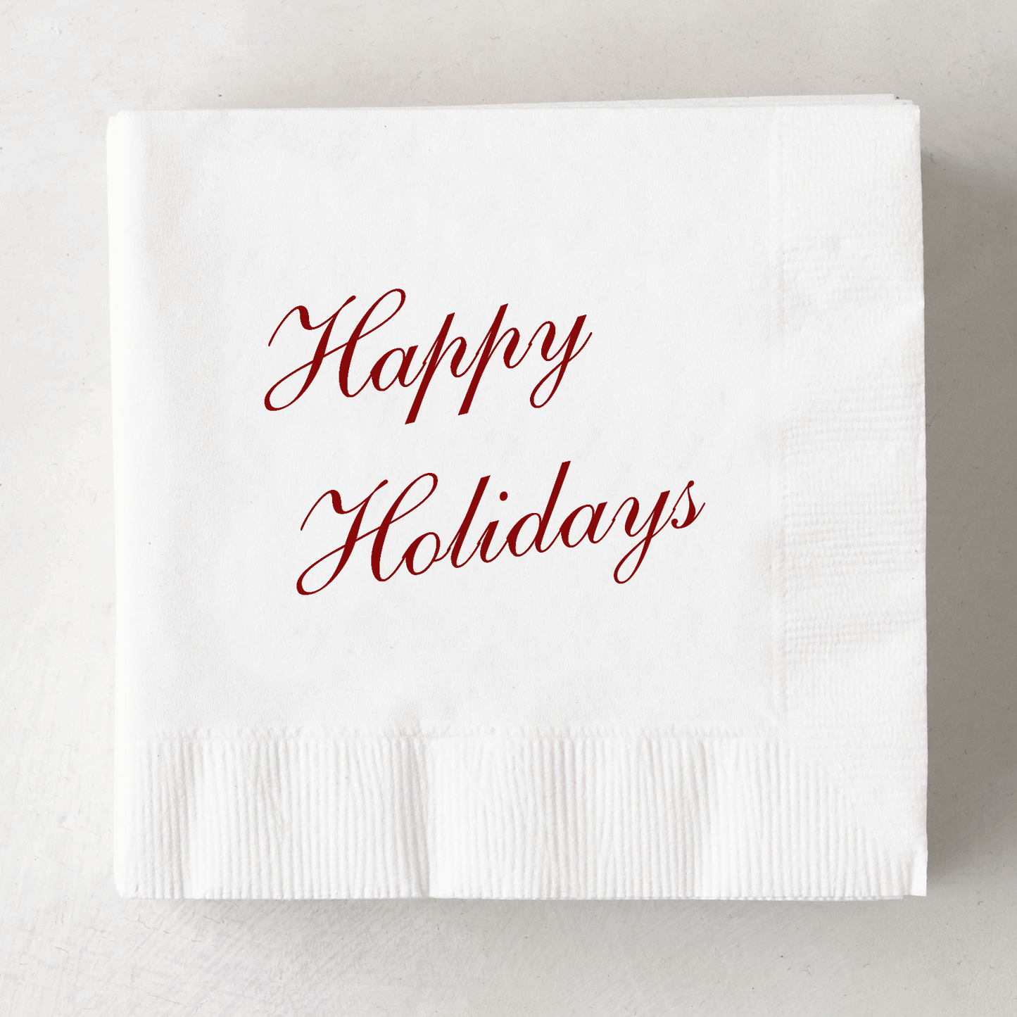 White 3-ply paper cocktail napkin with "Happy Holidays" in red script.