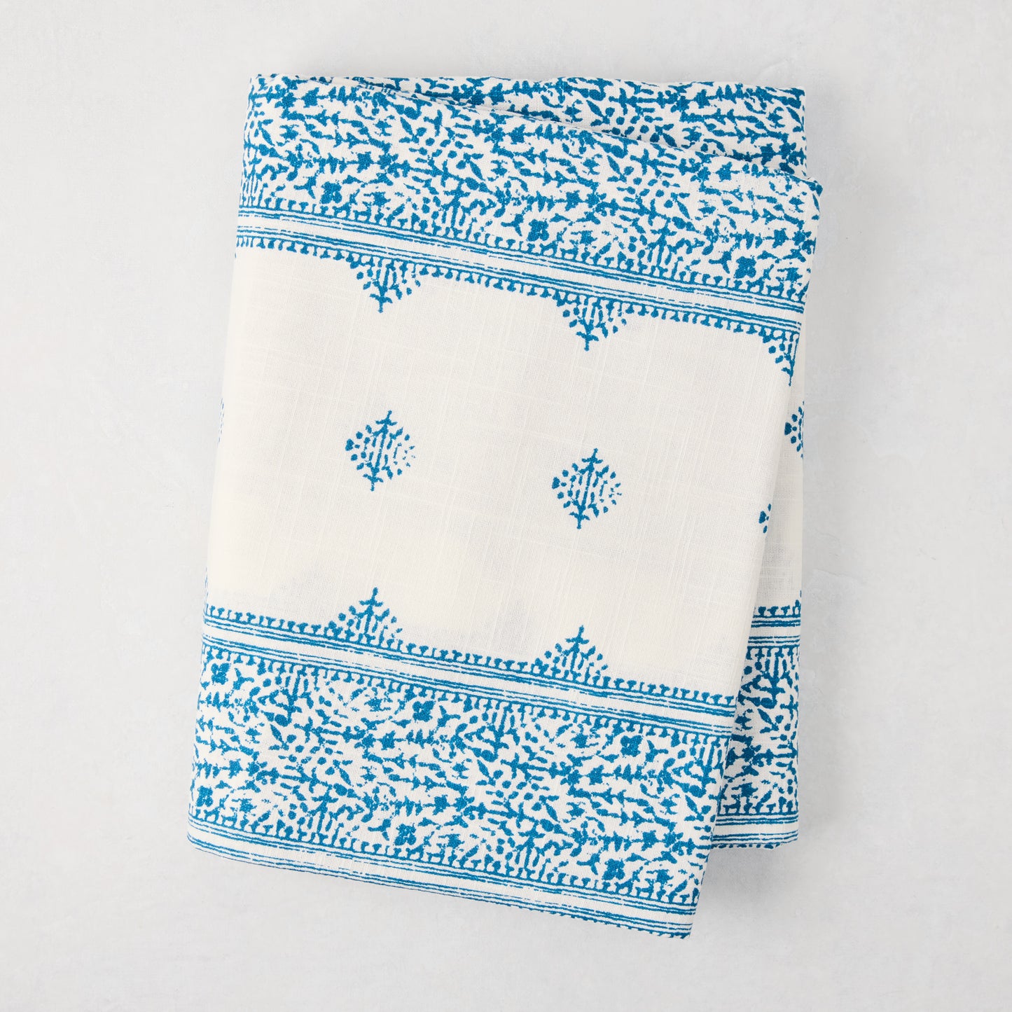 Peter Dunham + Hudson Grace Blue Fez Stripe 100% cotton slub tablecloth, folded, with intricate blue pattern.