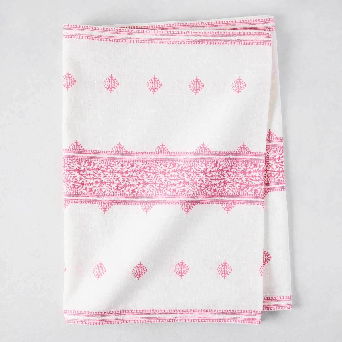Bright pink Fez printed cotton slub table runner, folded, with intricate patterns on white.