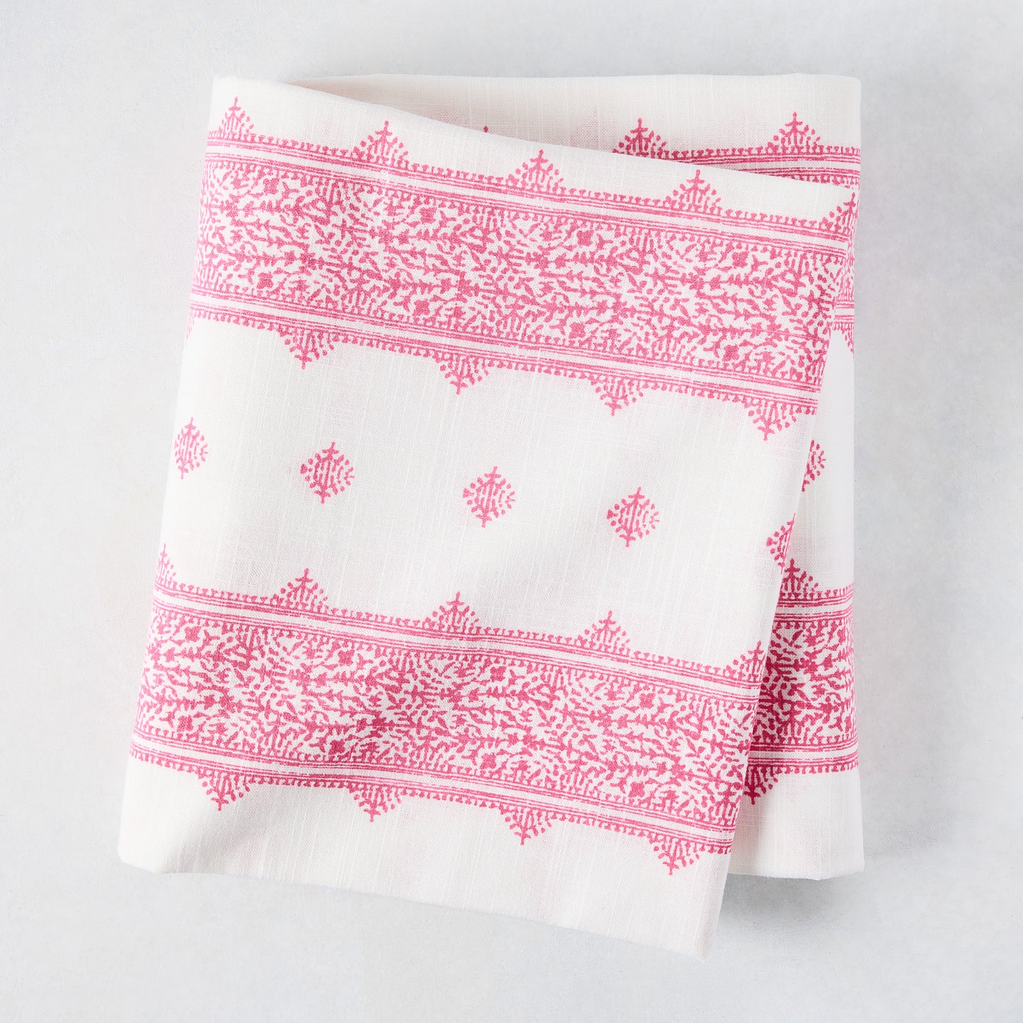 Folded Peter Dunham + Hudson Grace Bright Pink Fez Stripe cotton slub tablecloth with intricate pattern.