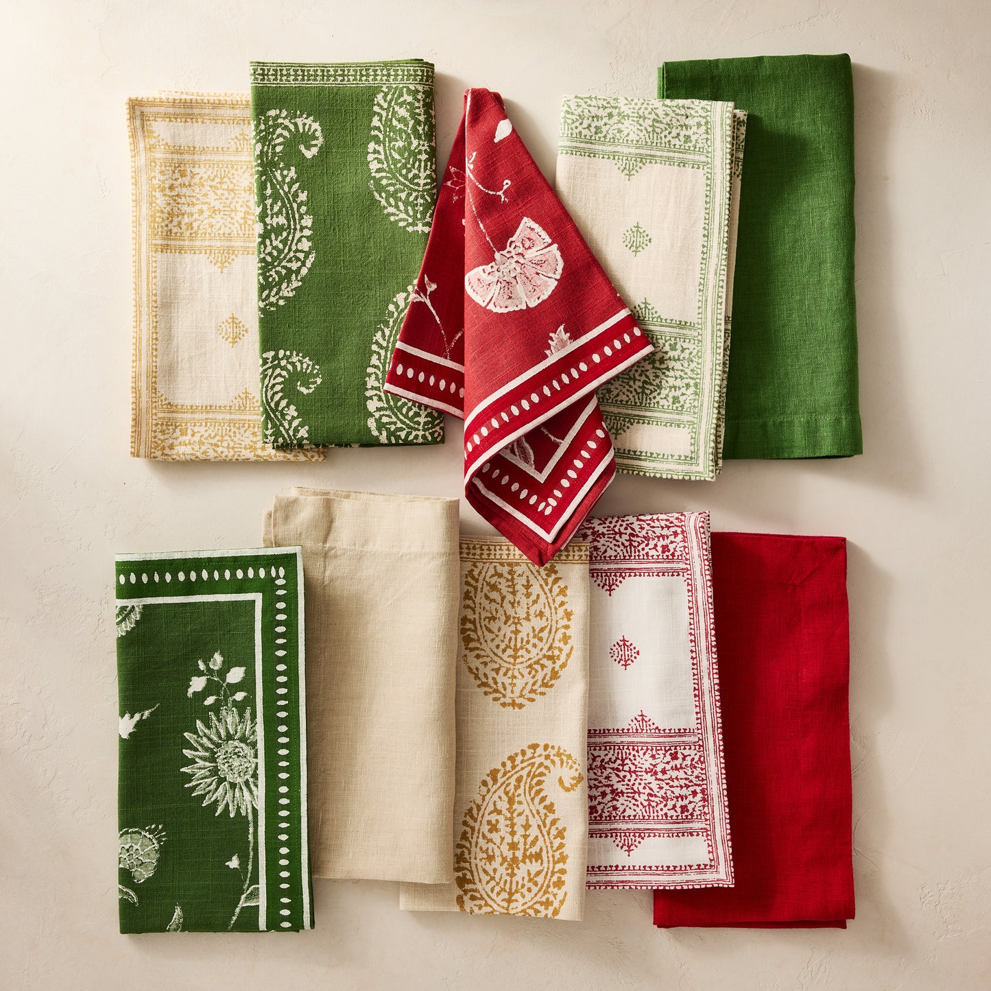 Peter Dunham + Hudson Grace Kashmir Paisley Olive Green Printed Napkin, folded with other patterned linens.