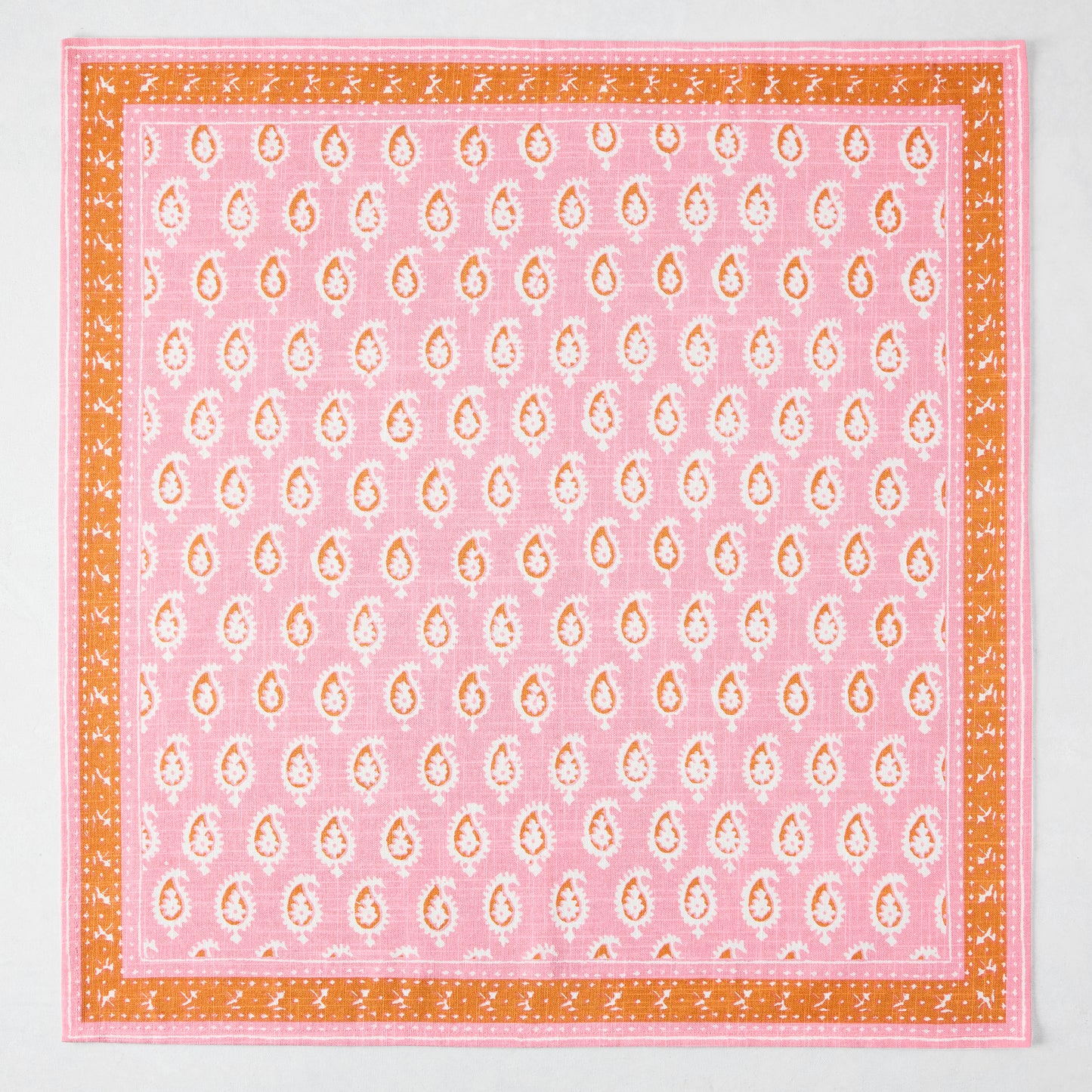Pink Janpath printed cotton slub napkin with white paisley pattern and orange graphic border.