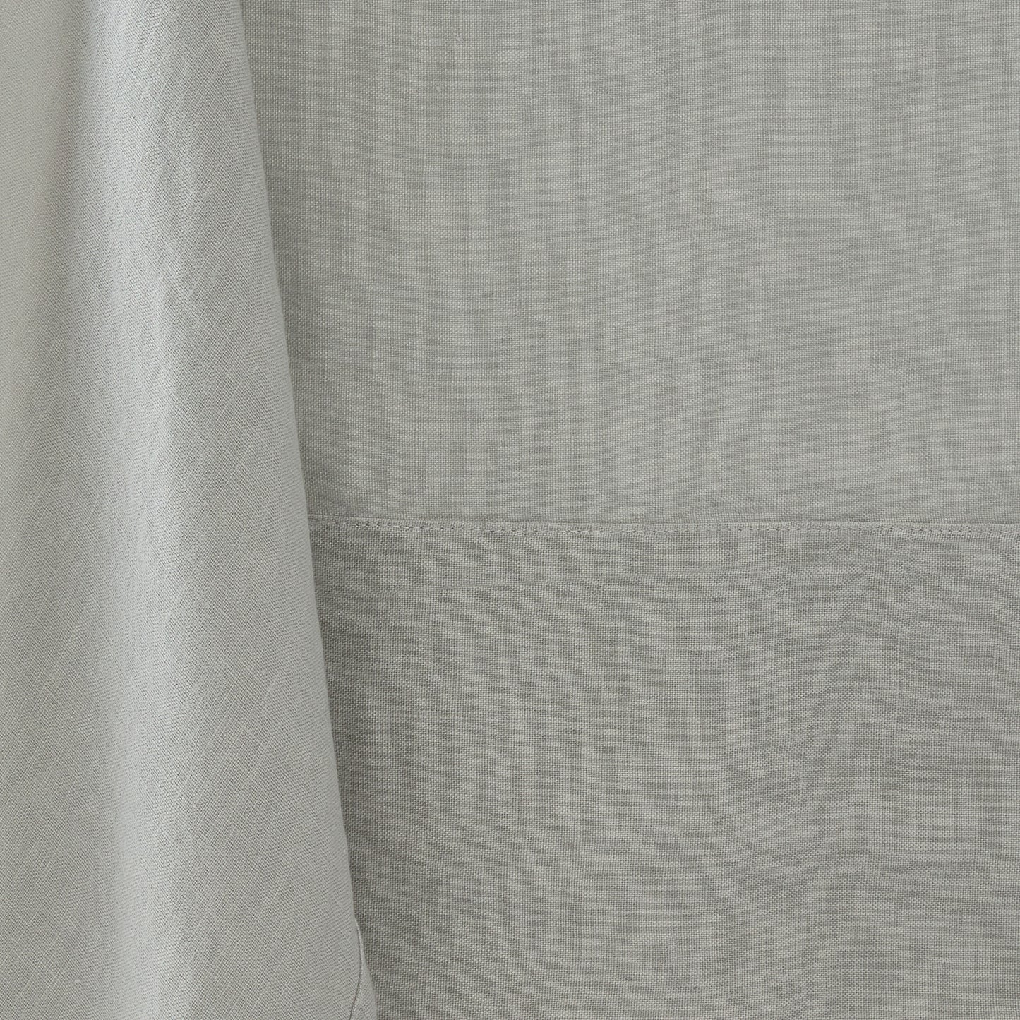 Hand-dyed grey linen tablecloth with visible fabric texture and a stitched border detail.
