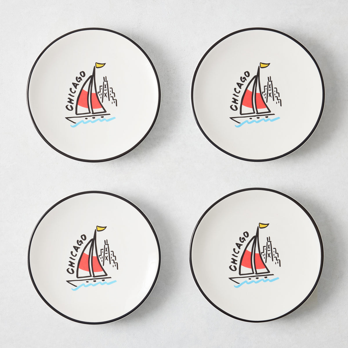 Set of four white appetizer plates with black rims and hand-painted Chicago sailboat illustrations by Rob Wilson.