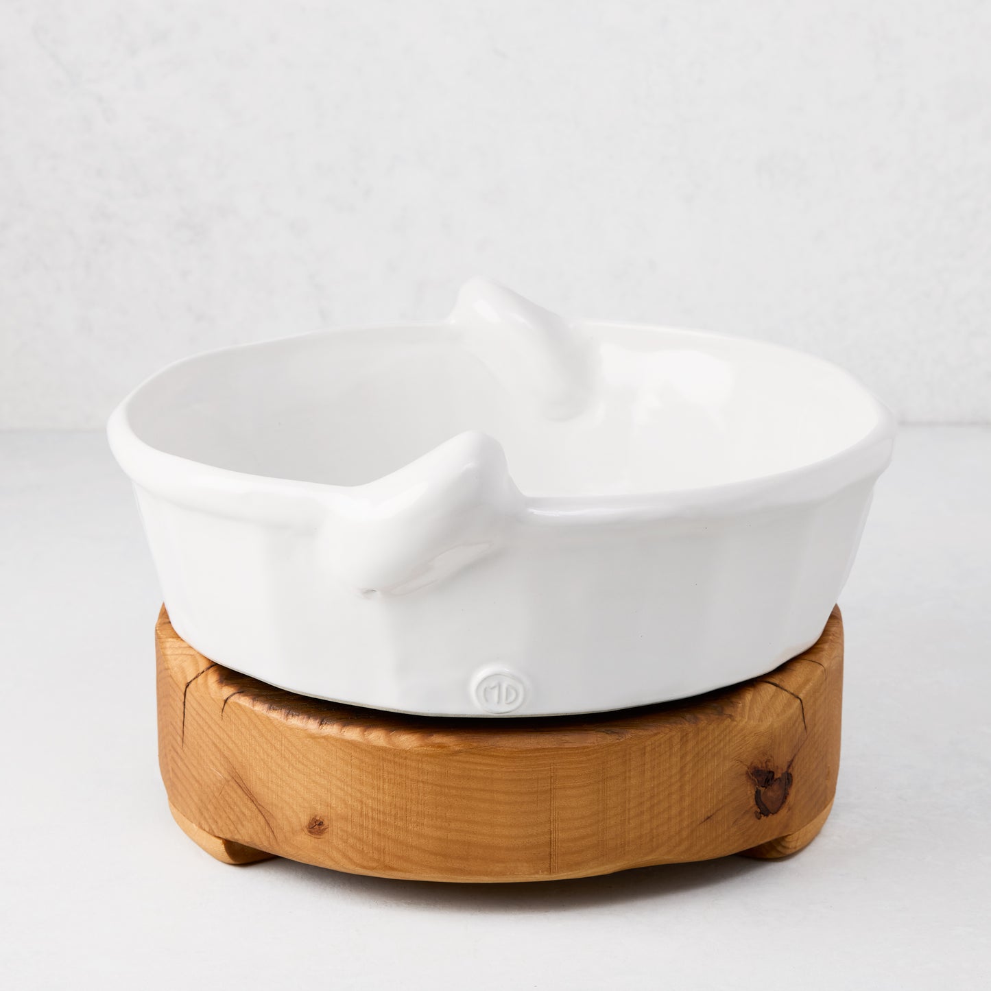 Round reclaimed pine wood footed trivet, 10"Dia x 3"H, with a white ceramic bowl on top.